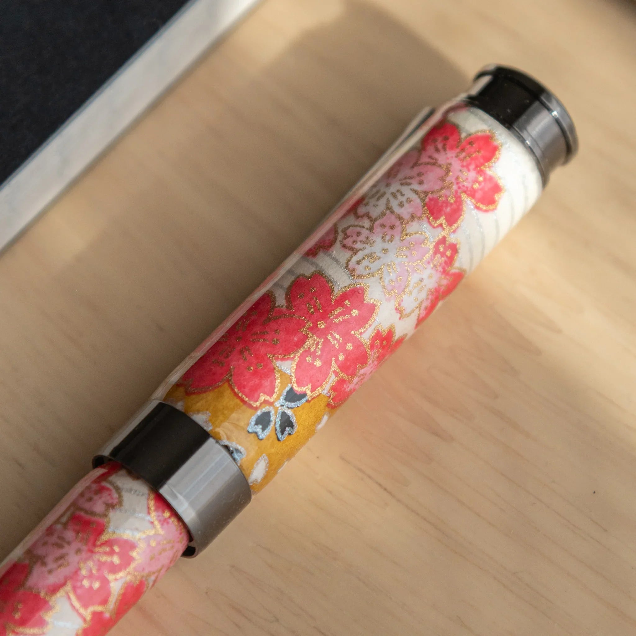 Akebono Cherry Mino Washi fountain pen barrel section with red cherry botanical details and metallic trim angle