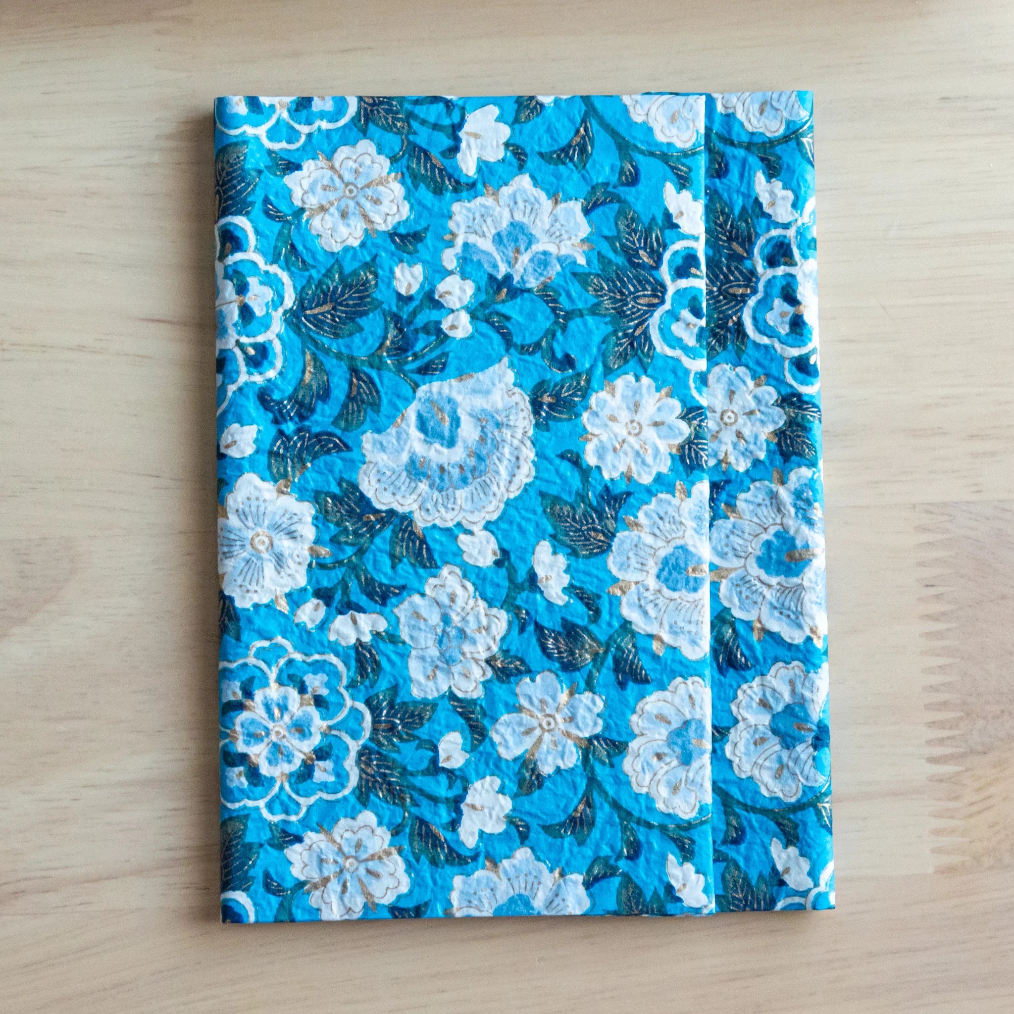 Blue garden hand-dyed yuzen washi book cover A6, closed view with white flower embroidered pattern overhead hues