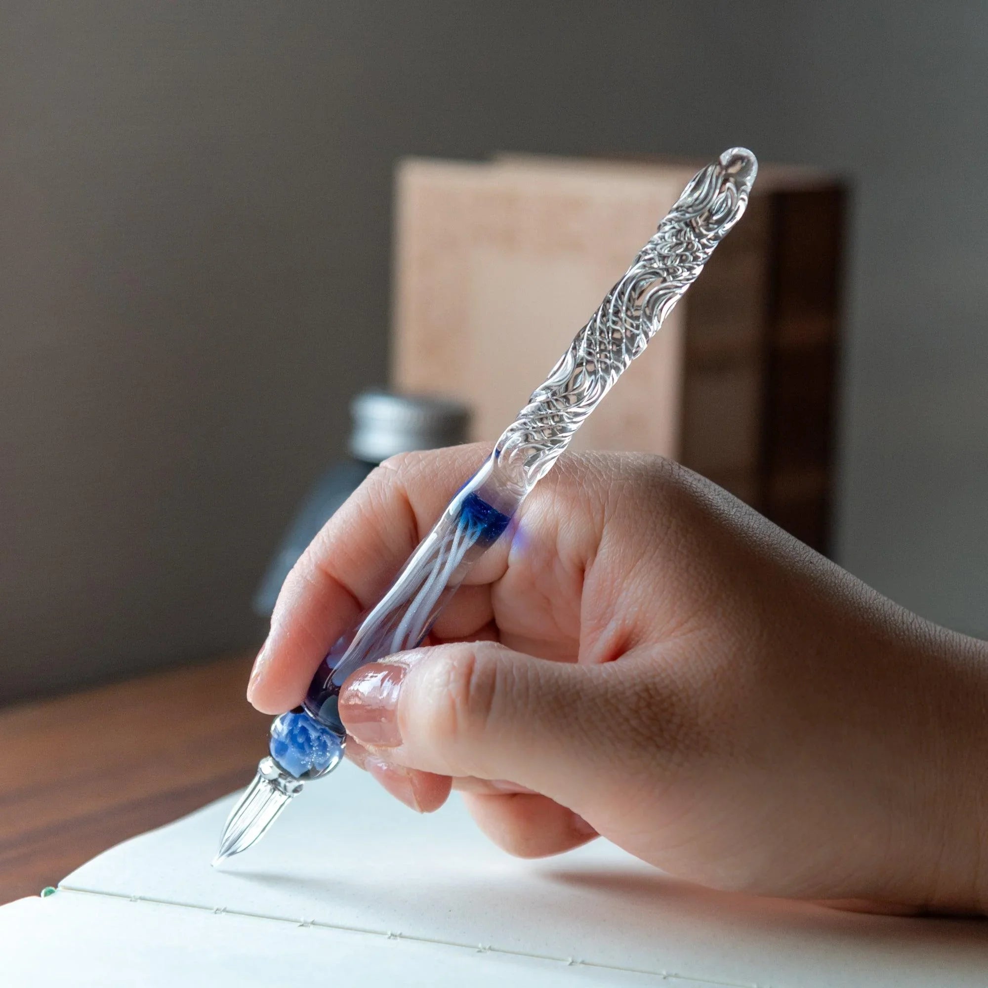 Deep blue rose glass dip pen with twisted metal nib displayed at angle showing rich dark blue coloring with holder