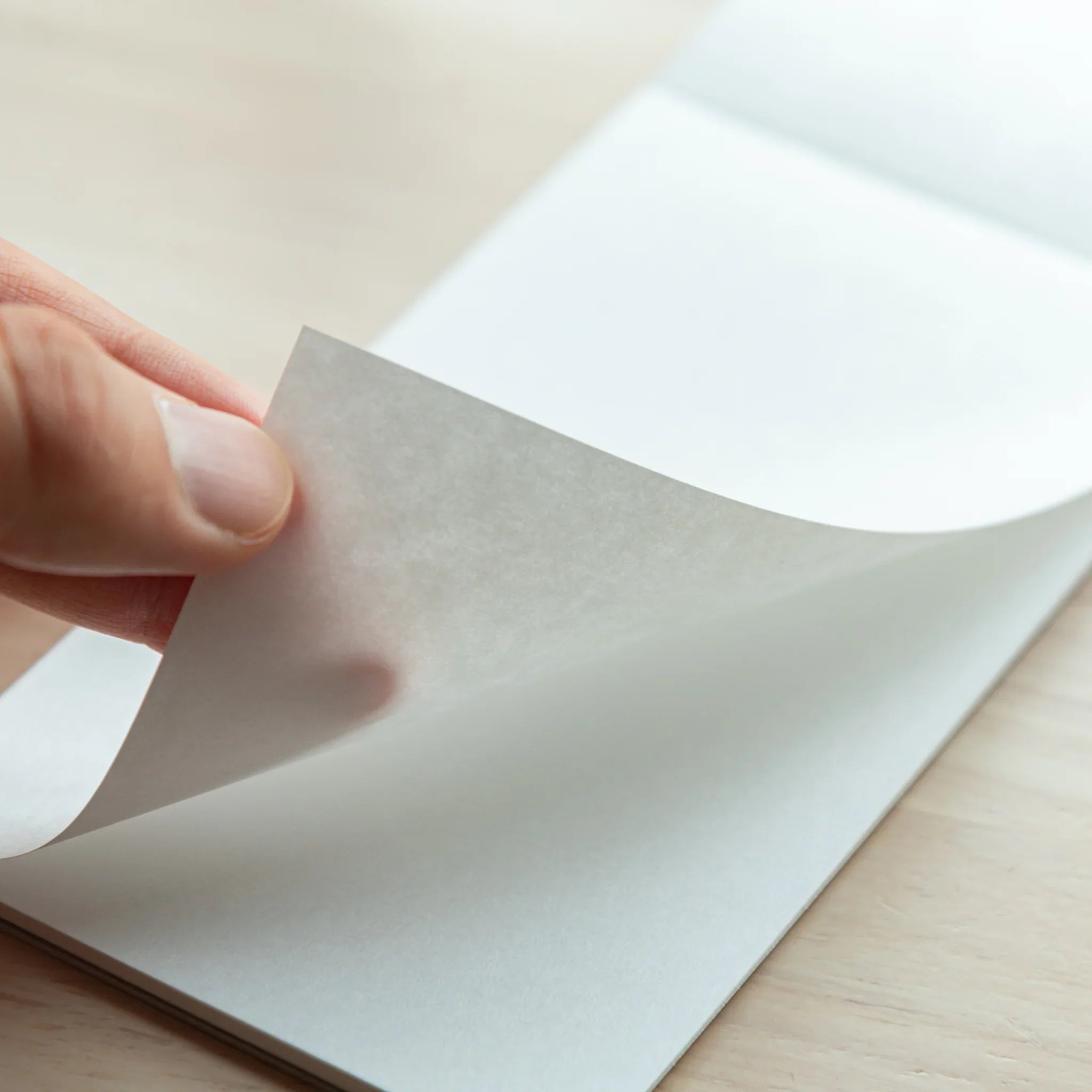 Hand peeling a page from Bullet Jotter writing pad, showing bright white Soliste paper texture and page separation