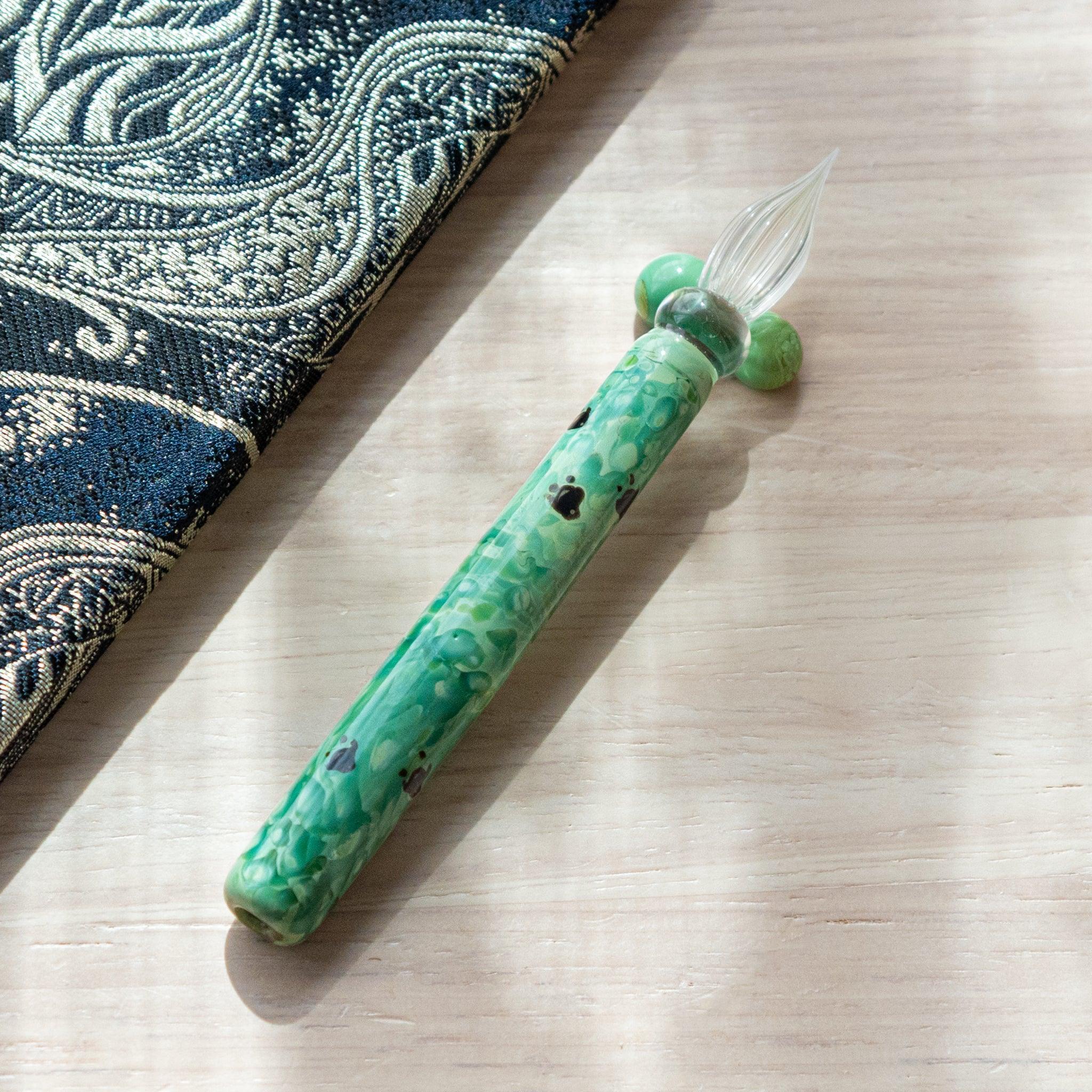 Emerald green glass dip pen with chidori plover bird pattern showing pen rest holder visible in background shown