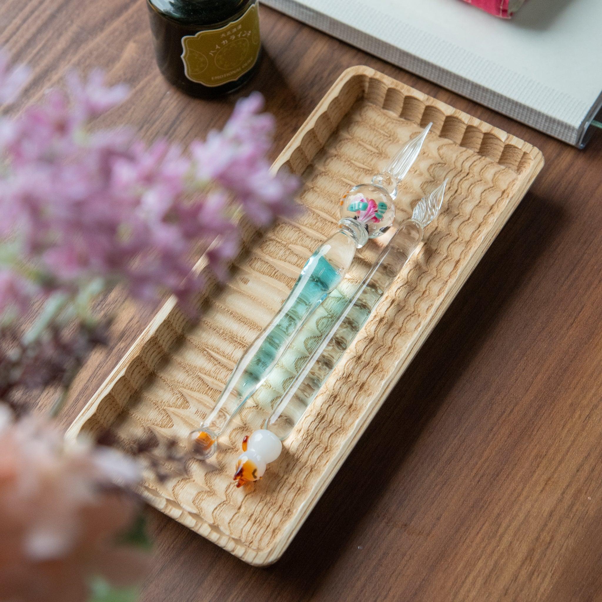 Clownfish pen resting in light wood carved tray with multiple pens displayed overhead view with handle detail and decorative