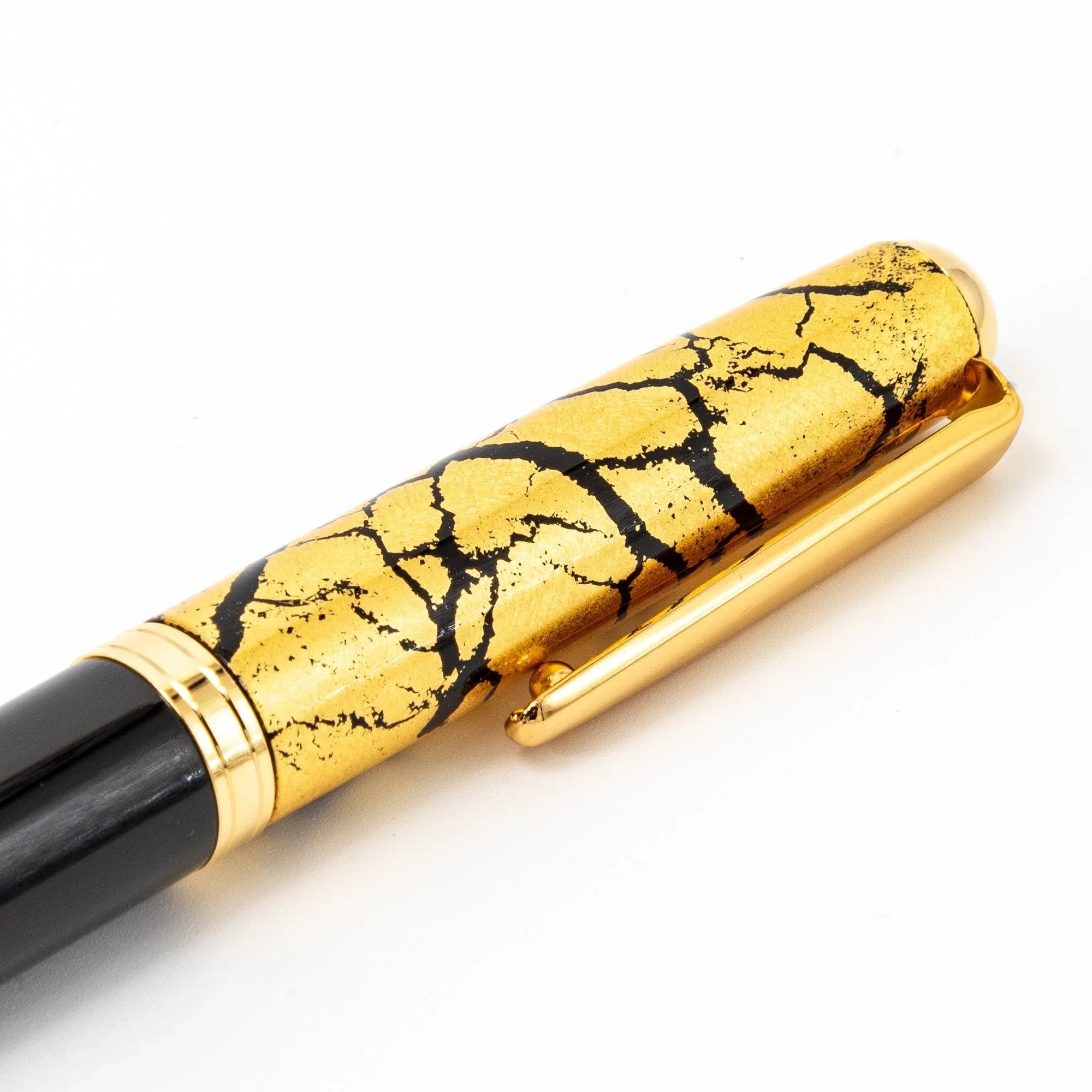 Black fountain pen uncapped showing gold crackle on barrel and nib section, detailed lacquer shot view