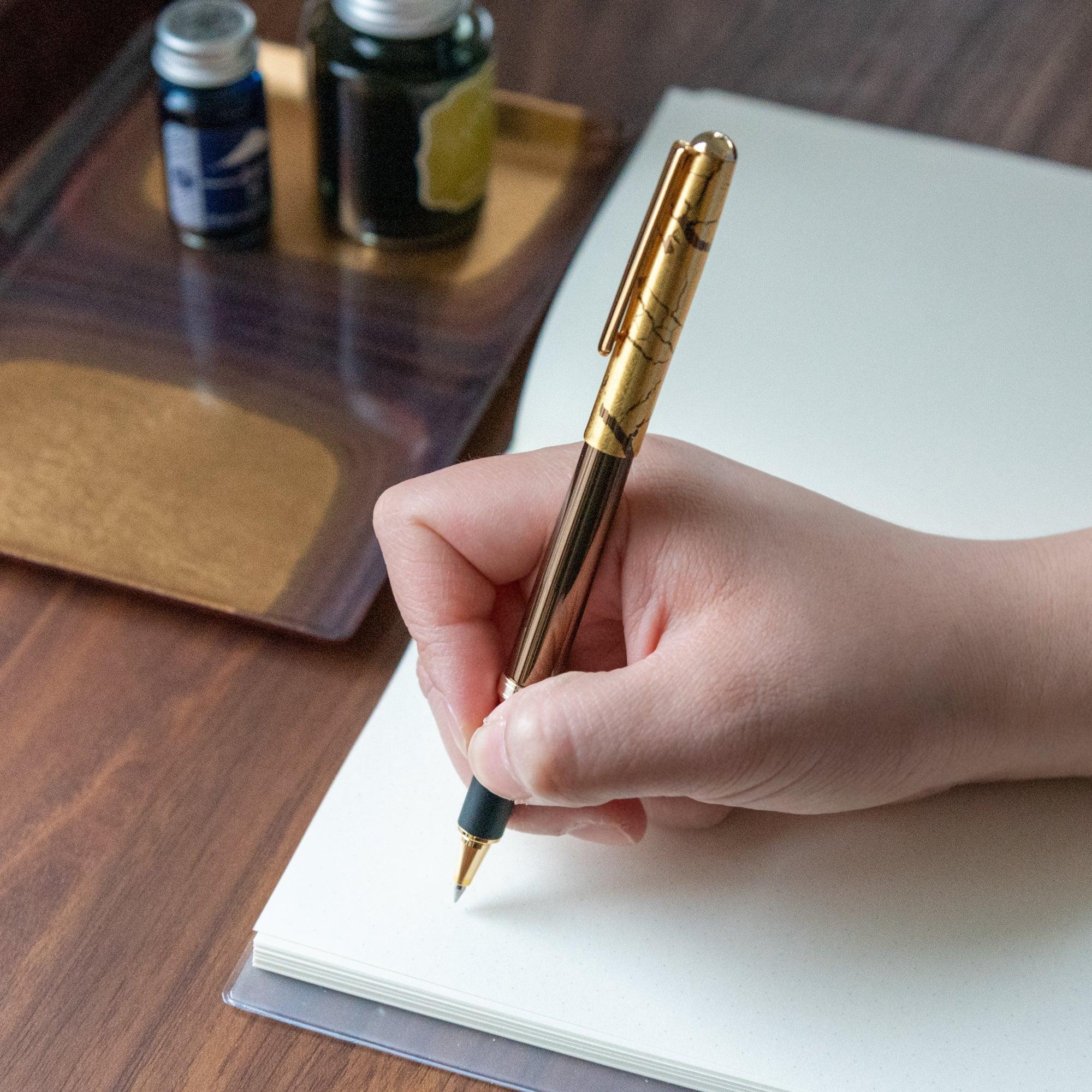 Japanese crack pattern gold leaf brown ballpoint pen with gold crackle cap displayed beside uncapped barrel