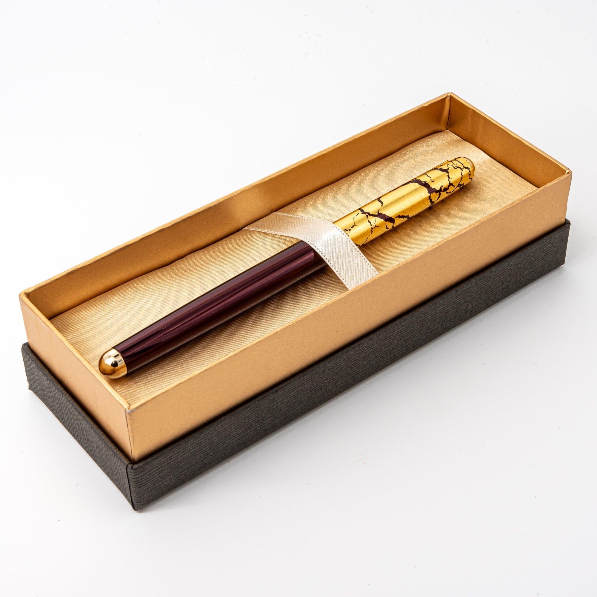 Japanese wine red ballpoint pen held over notebook on wooden desk surface, in-use writing demonstration