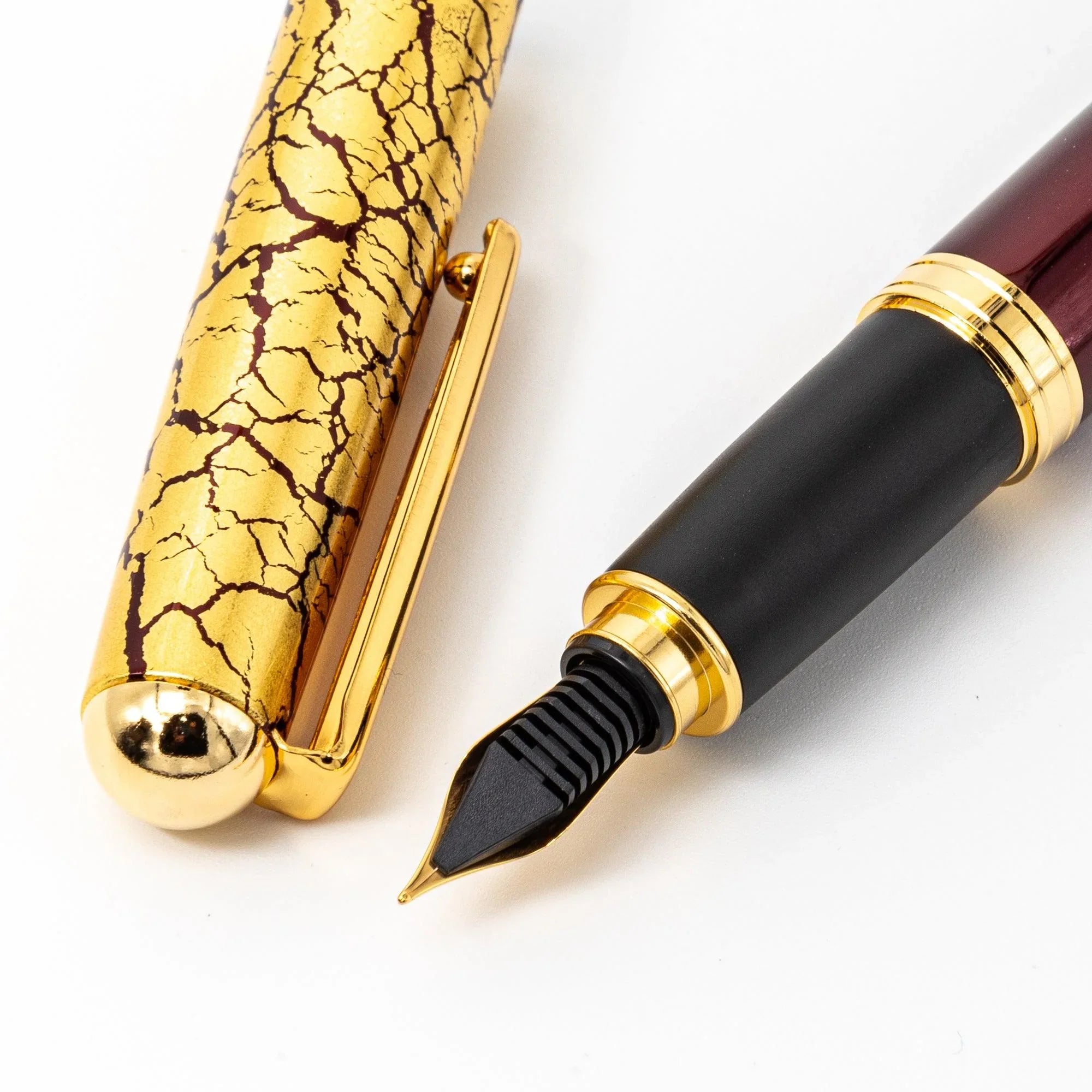 Wine red fountain pen macro close-up detail showing fine gold crackle pattern on glossy burgundy lacquer