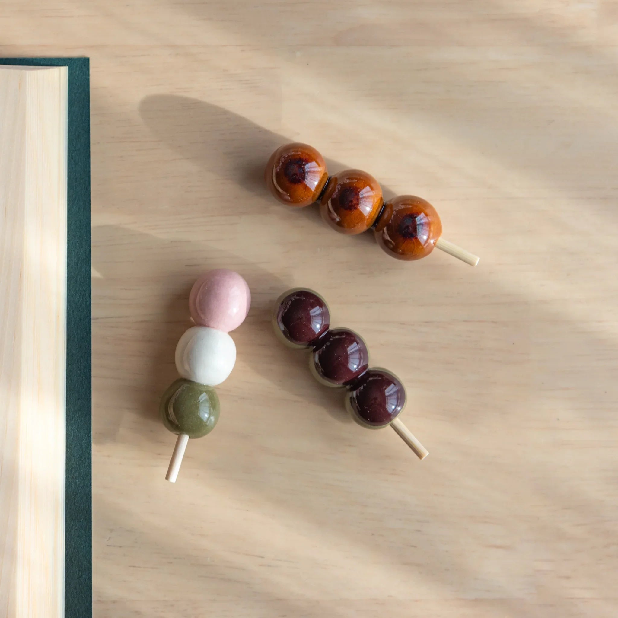 Three-tier dango handcrafted ceramic pen rest with brown wooden skewer and stacked spherical ceramic pieces detail