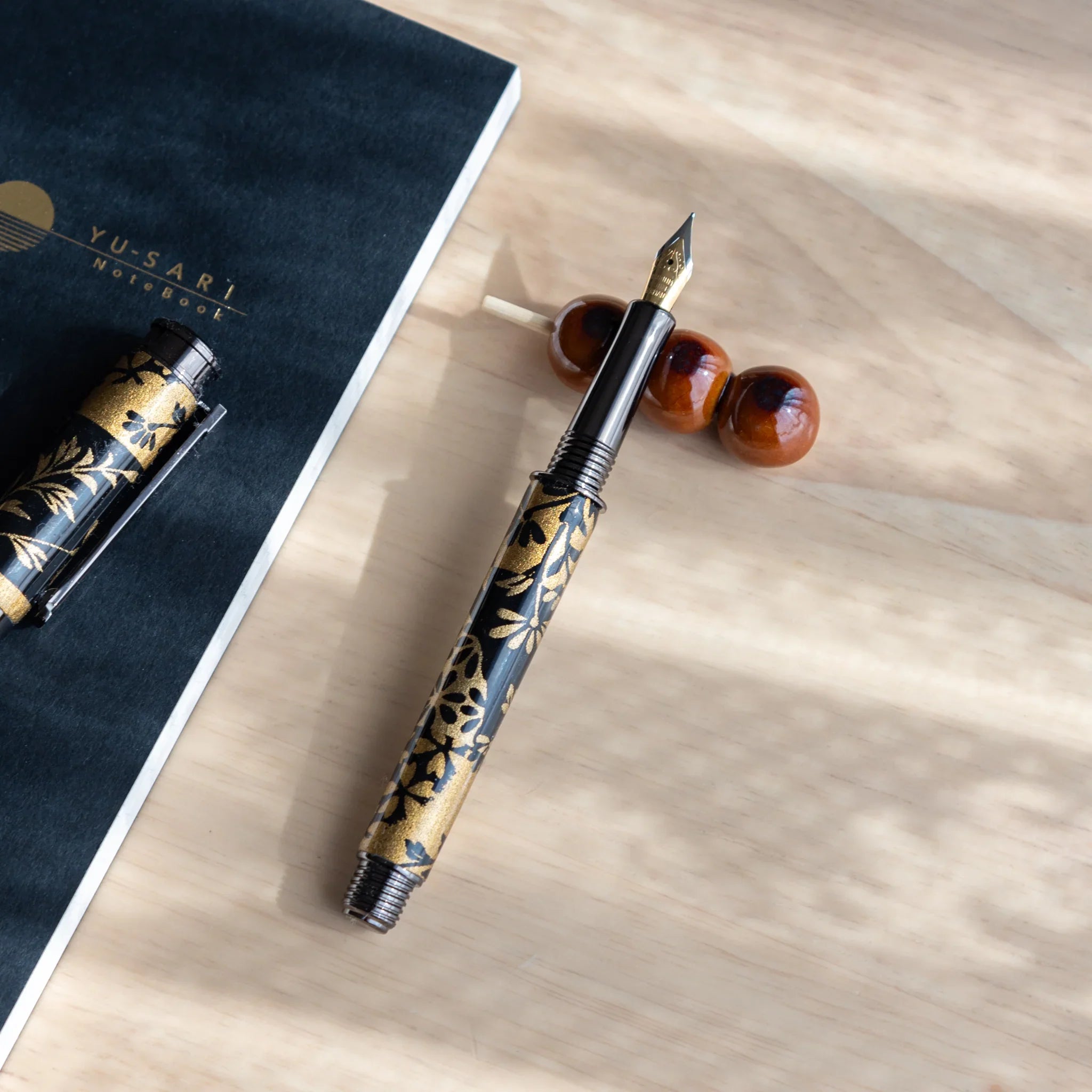 Orange toned three-bead dango pen rest with spherical beads stacked vertically on clear glass stem with spacers