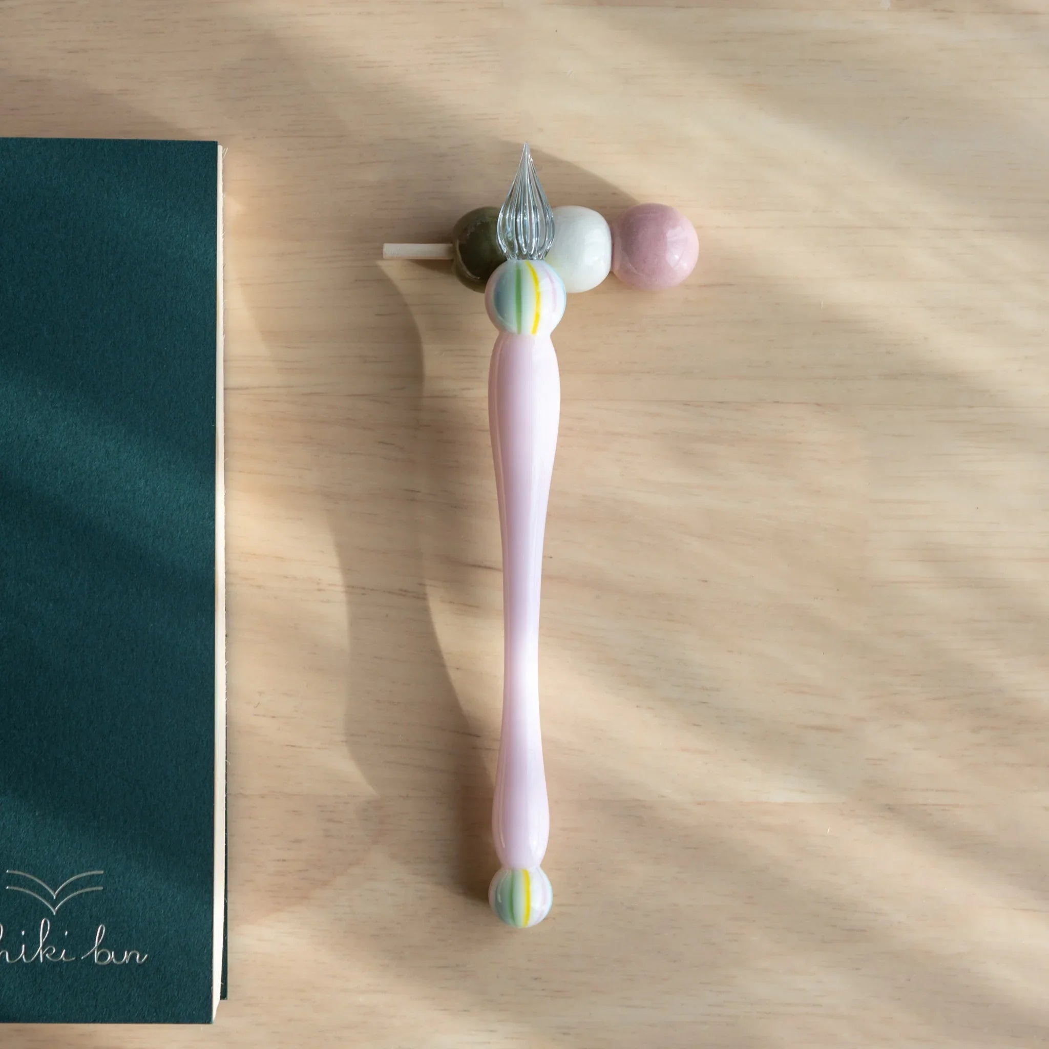 Brown and white dango-shaped handcrafted ceramic pen rests with wooden skewer support on display surface close shot