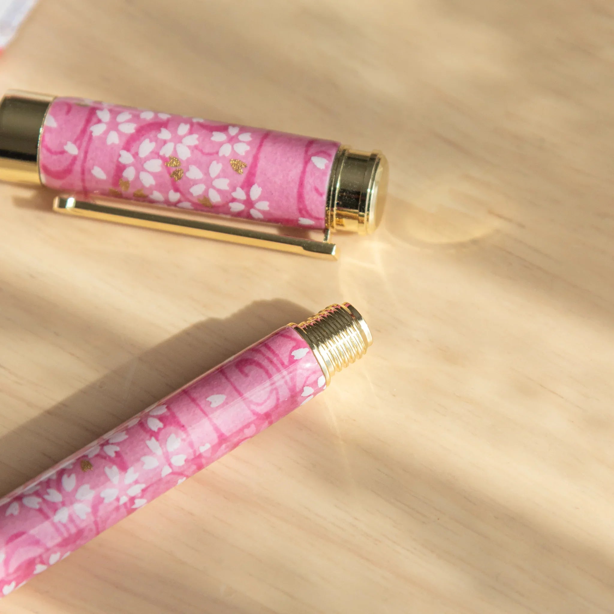 Close-up of the cap and barrel of a pink Mino washi Japanese fountain pen with white sakura print and gold metal fittings