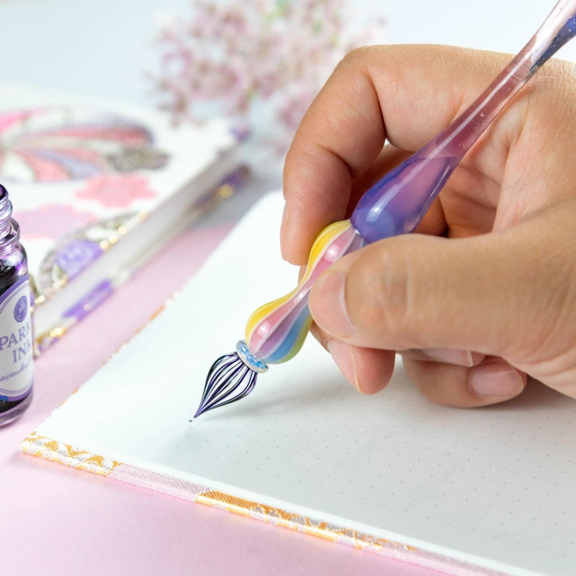 Rose glass dip pen positioned with ink bottle demonstrating ink holding capacity and usage potential