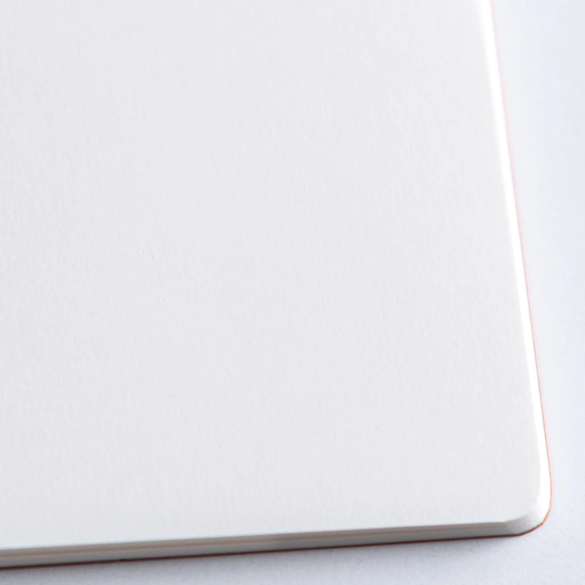 Orange Dressco A6 notebook with white product wrapper showing detailed product information text printed in Japanese