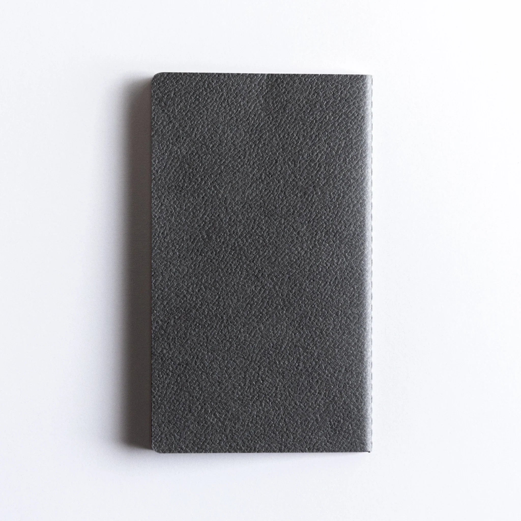 Charcoal A6 notebook pages fanned in cascade showing thickness of paper and total page count of complete notebook