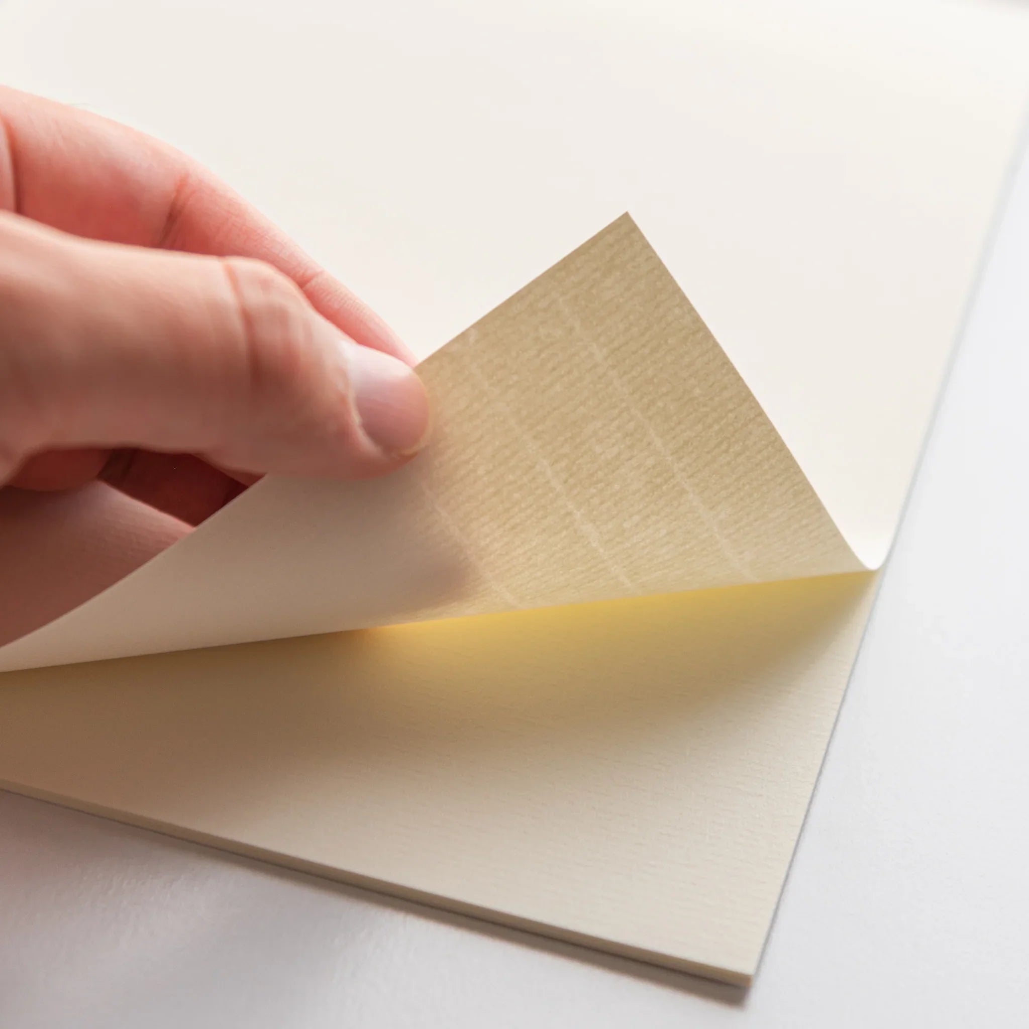 Cream writing pad positioned at angle revealing fold and laid paper characteristic texture pattern composition shown