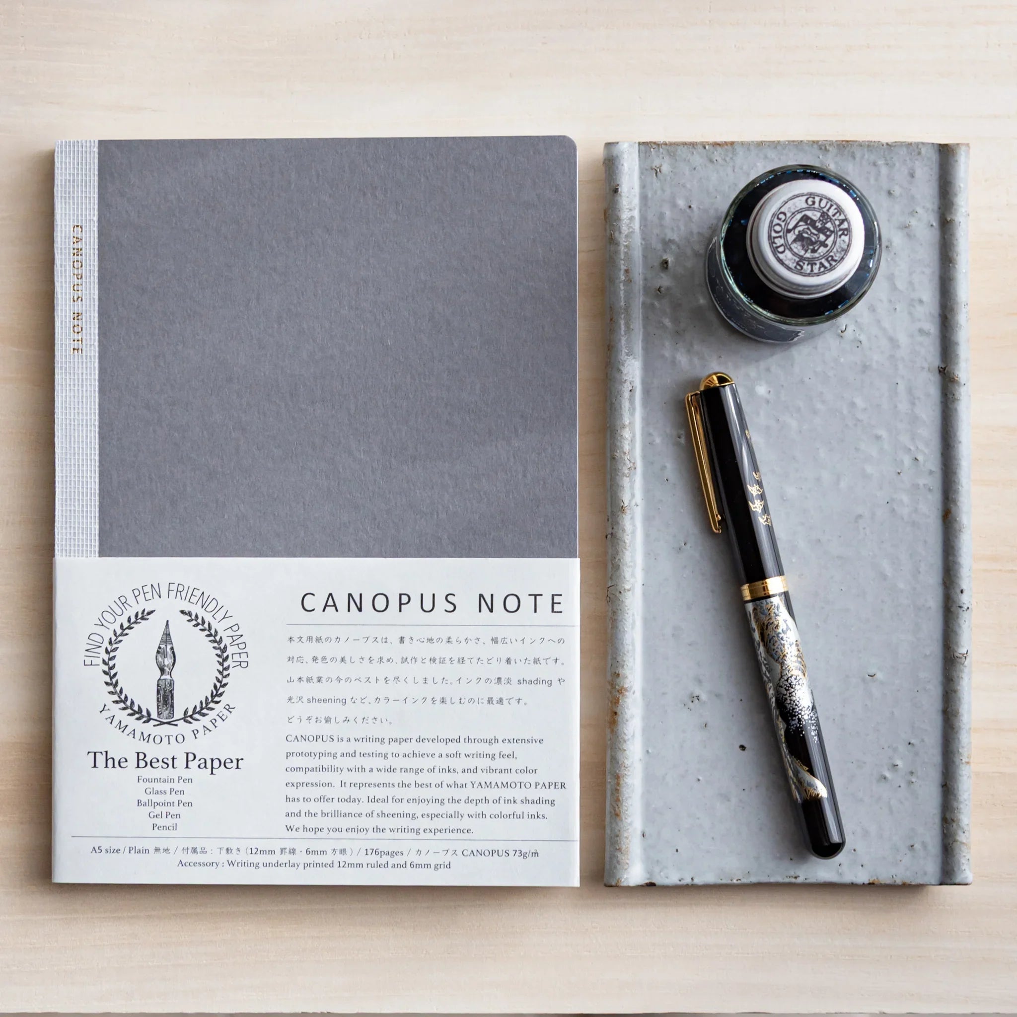 Japanese ceramic pen tray on light neutral surface with ink bottle and fountain pen displayed displayed clearly