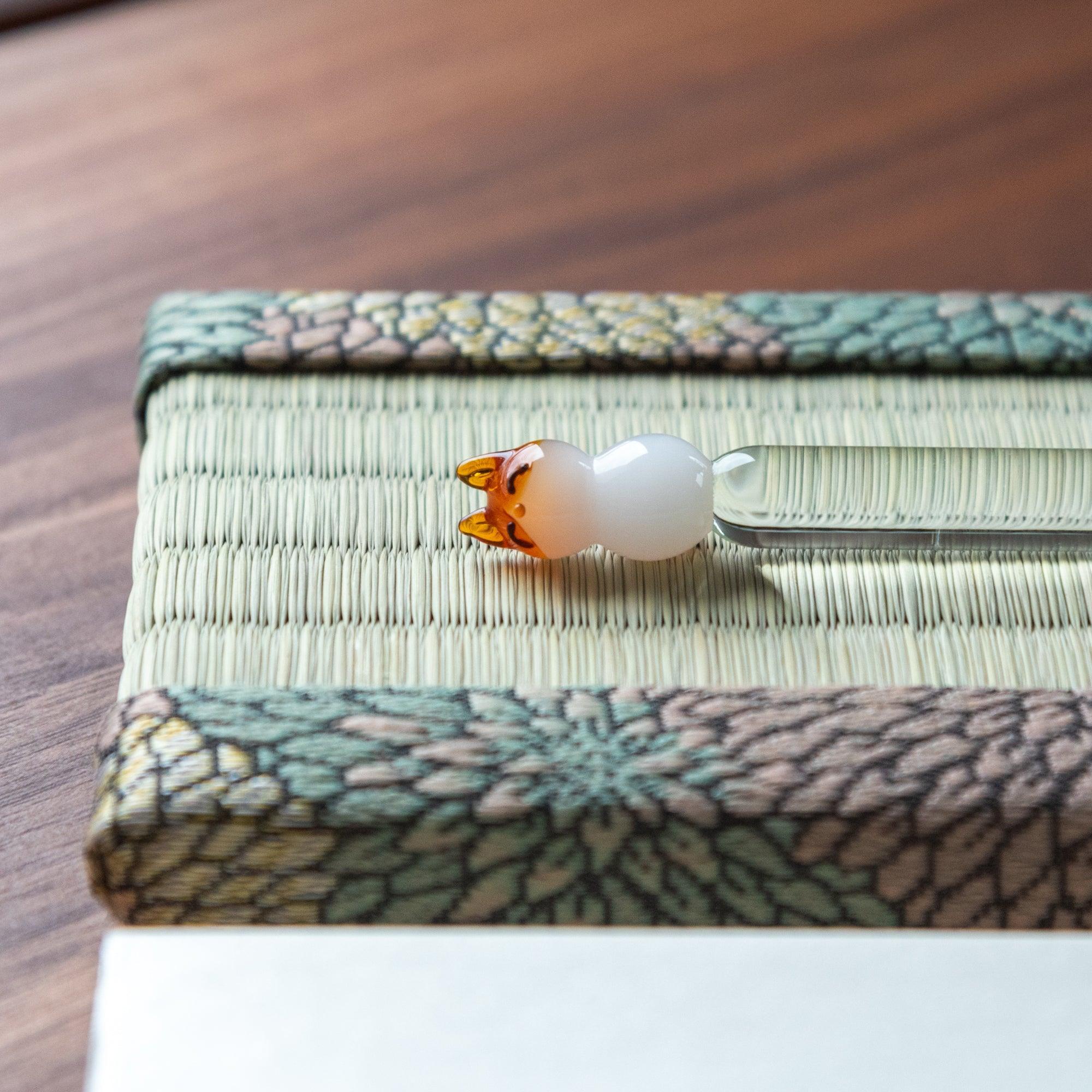 Angled close-up of Chrysanthemum Tatami Pen Tray showing brocade border and glass bird-top pen on tatami surface