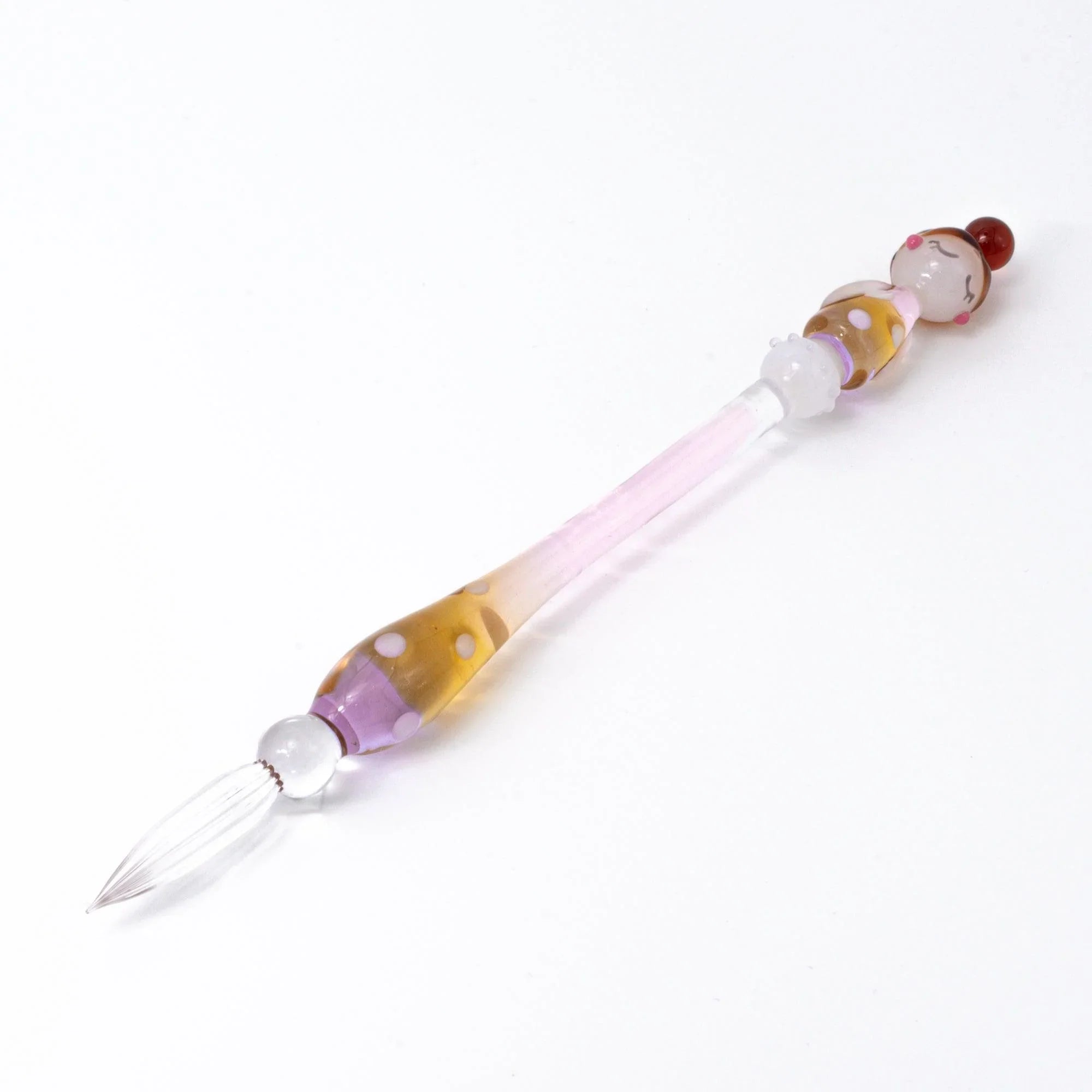 Marun-Chan glass dip pen displaying reddish character head and yellow purple spotted glass with handle detail and decorative
