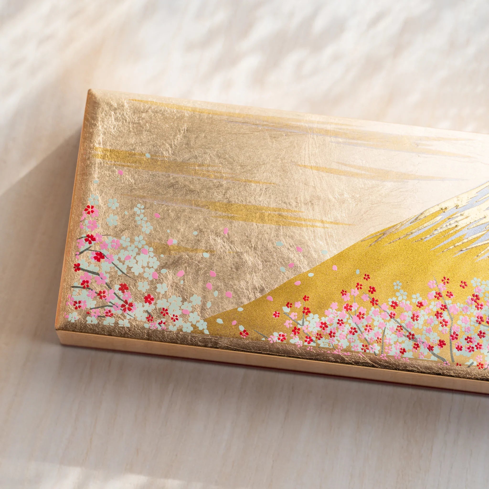 Gold pen case in closed form showing complete Mt. Fuji and cherry blossom design pattern displayed clearly