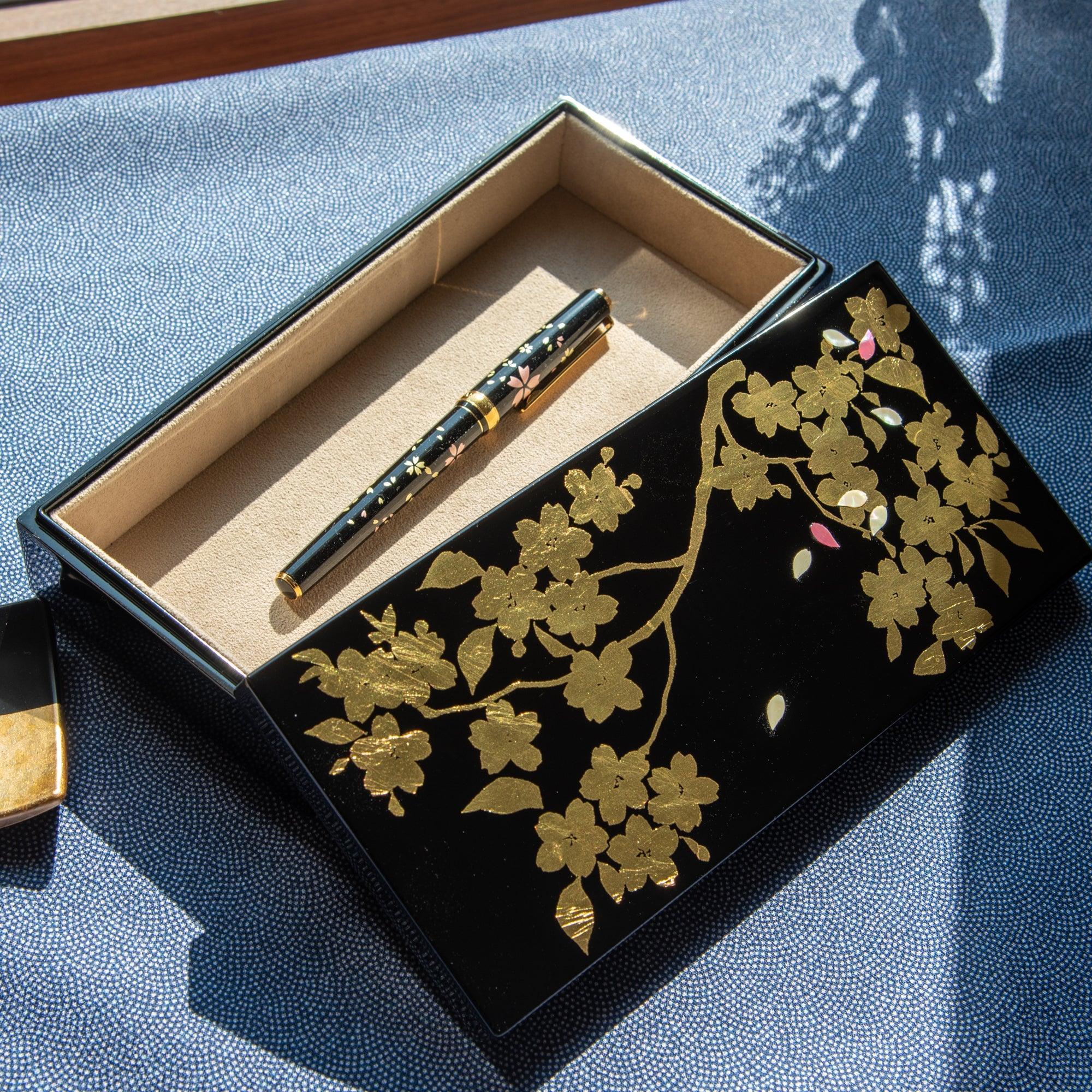Wooden pen box opened revealing dark interior compartments for pen storage displayed clearly composition