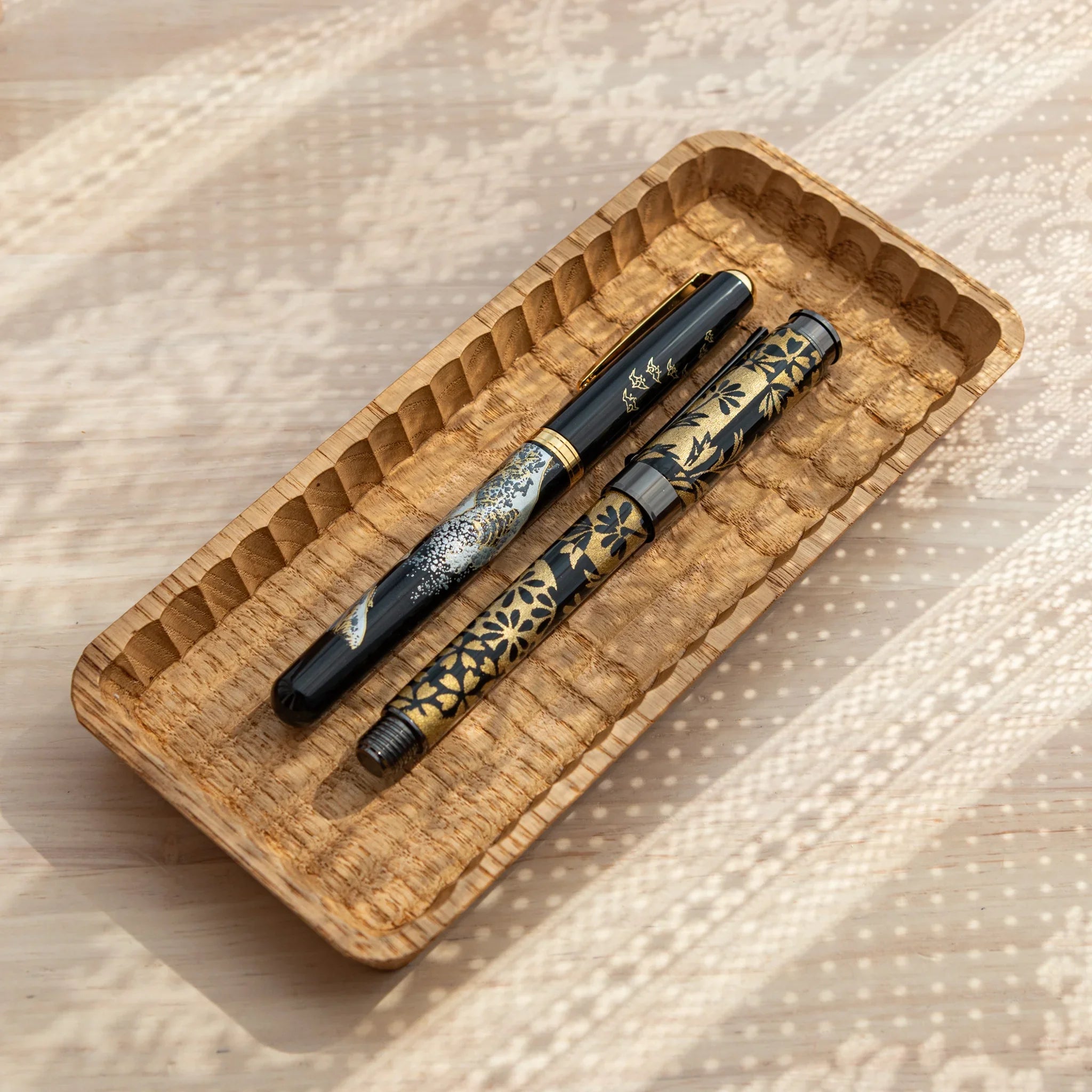 Wooden pen tray displayed holding decorative pens in hand-carved grooves displayed clearly composition