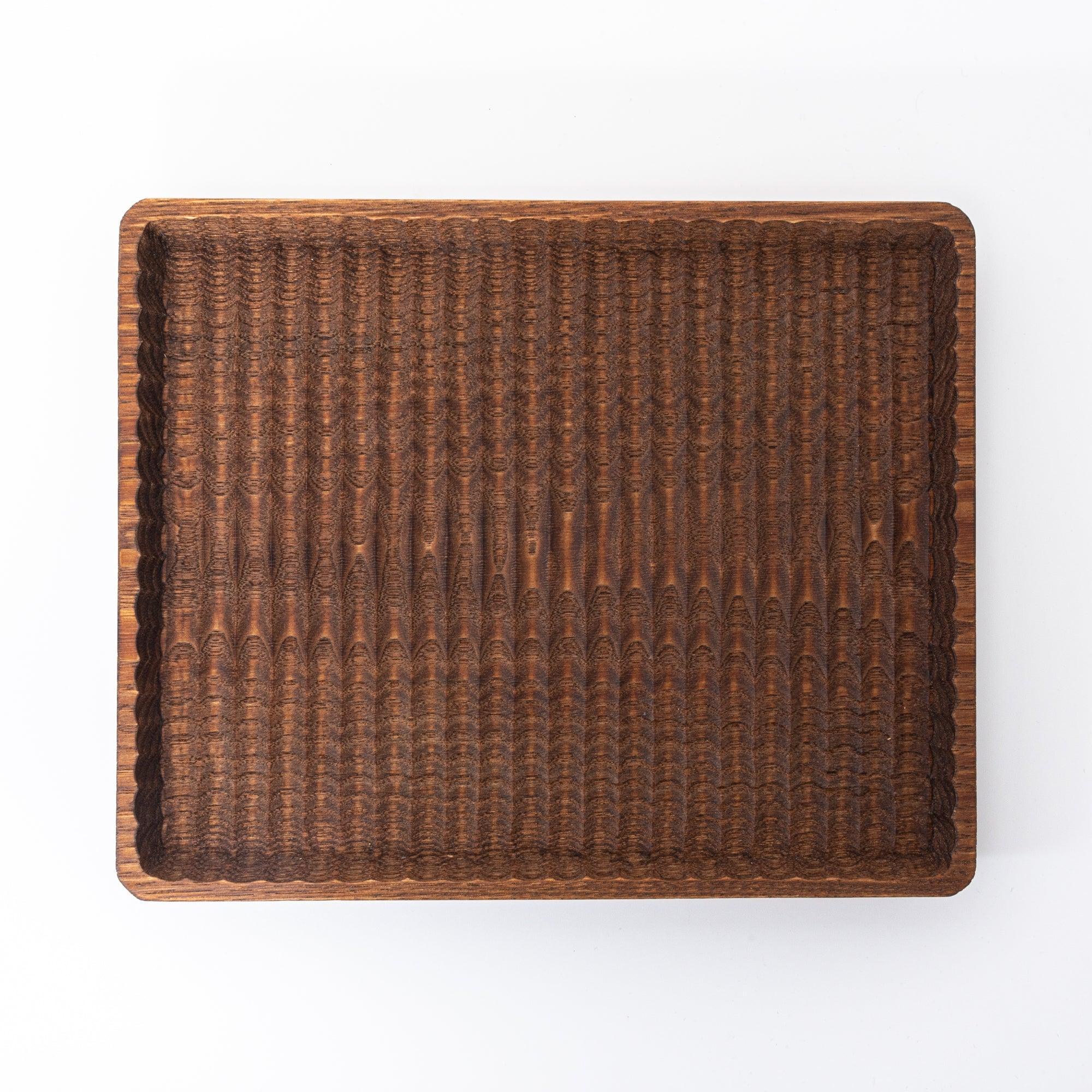 Wooden pen tray overhead shot with carved wave pattern and multiple decorative writing instruments with clear visibility of