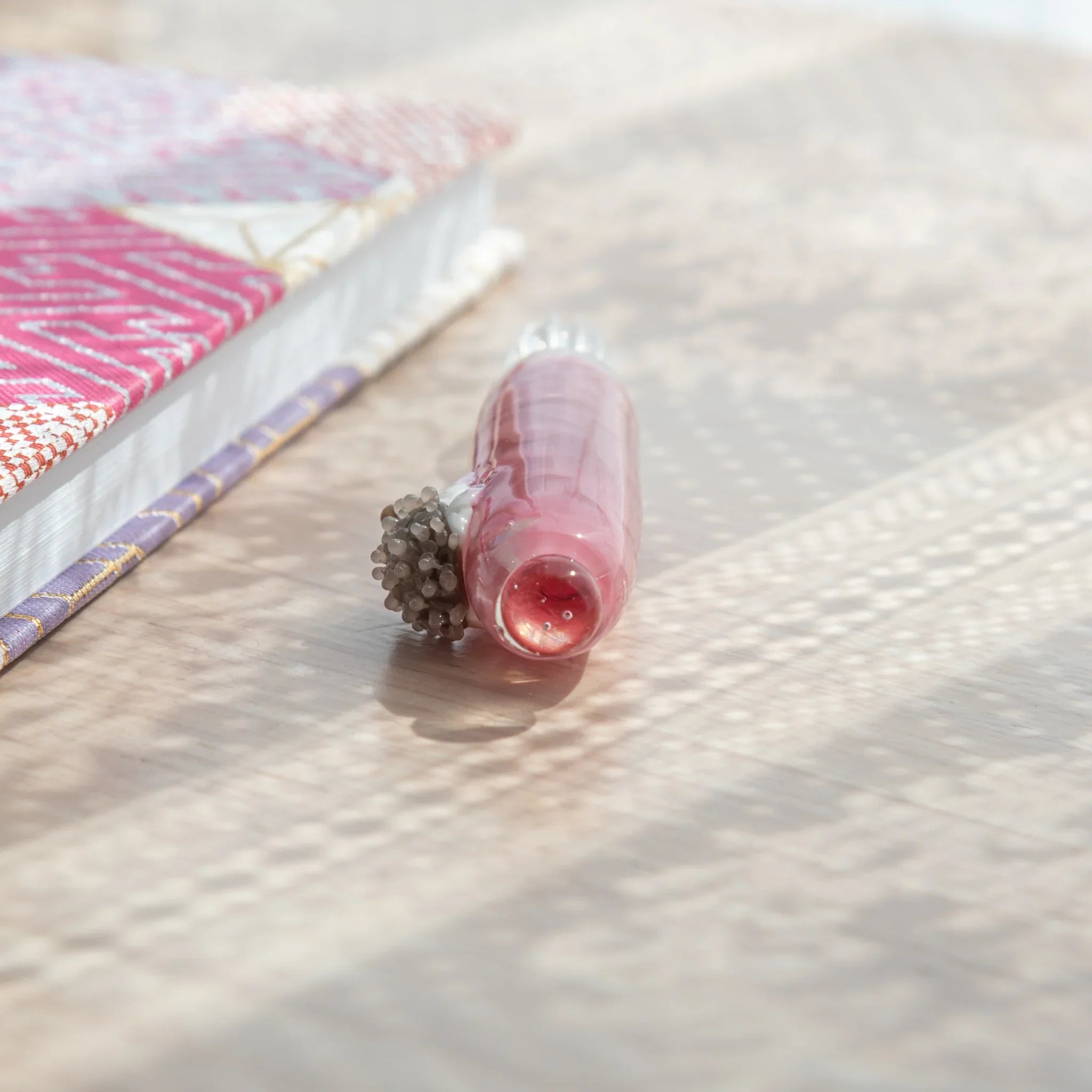 Glass dip pen with spiky hedgehog design on colorful hand-blown glass and sand-textured ceramic base