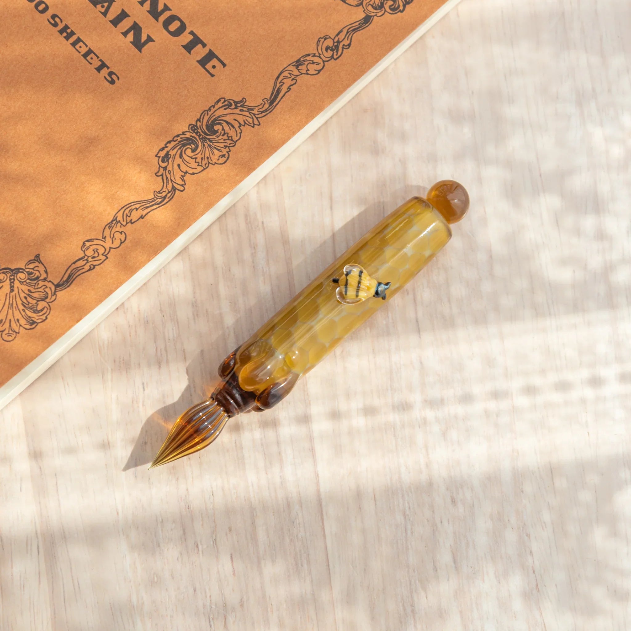 Honey bee glass dip pen with detailed insect perched on colorful hand-blown glass ink bottle with unique design