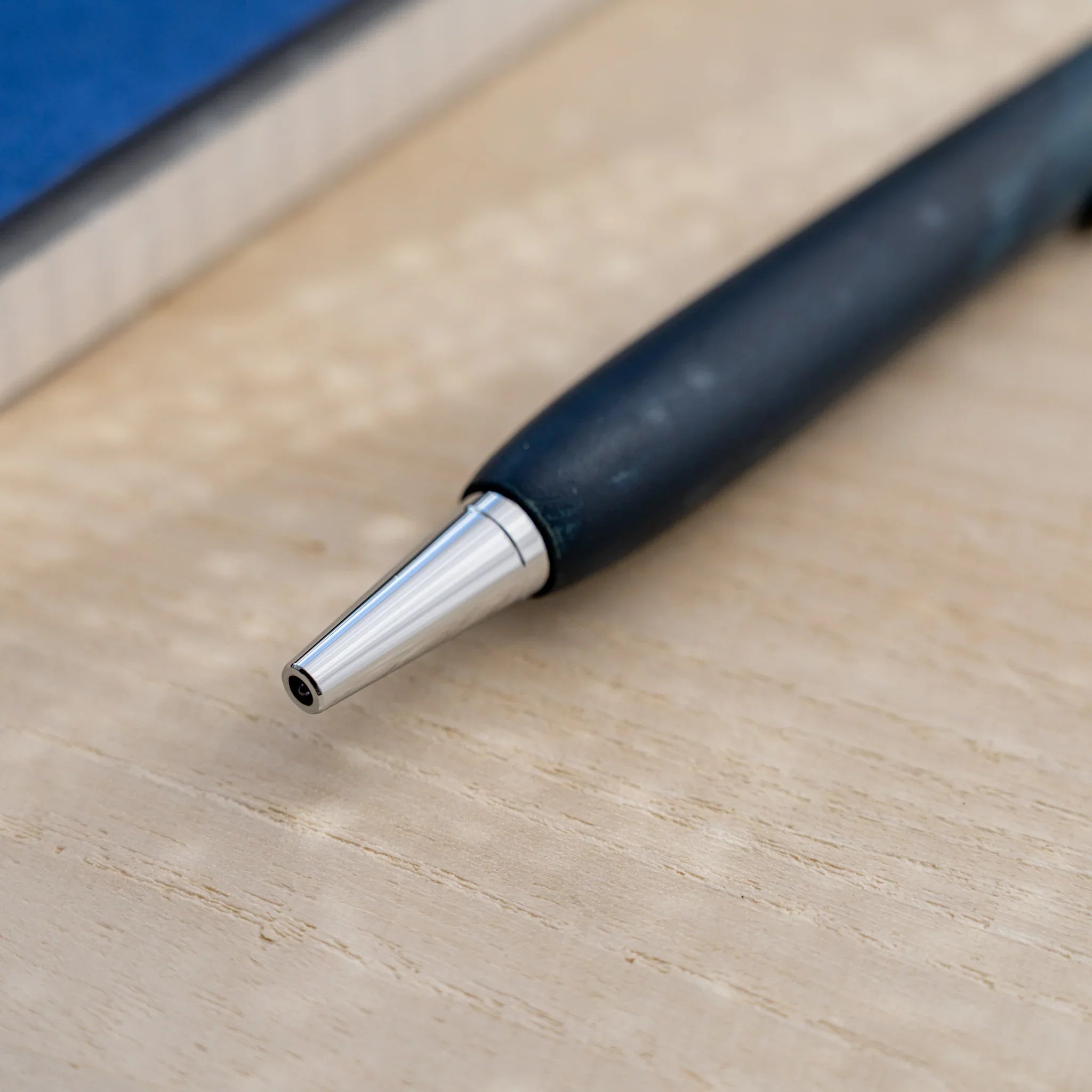 Indigo blue horse chestnut wood urushi ballpoint pen, close-up of lower barrel and silver cone tip, Japanese wood