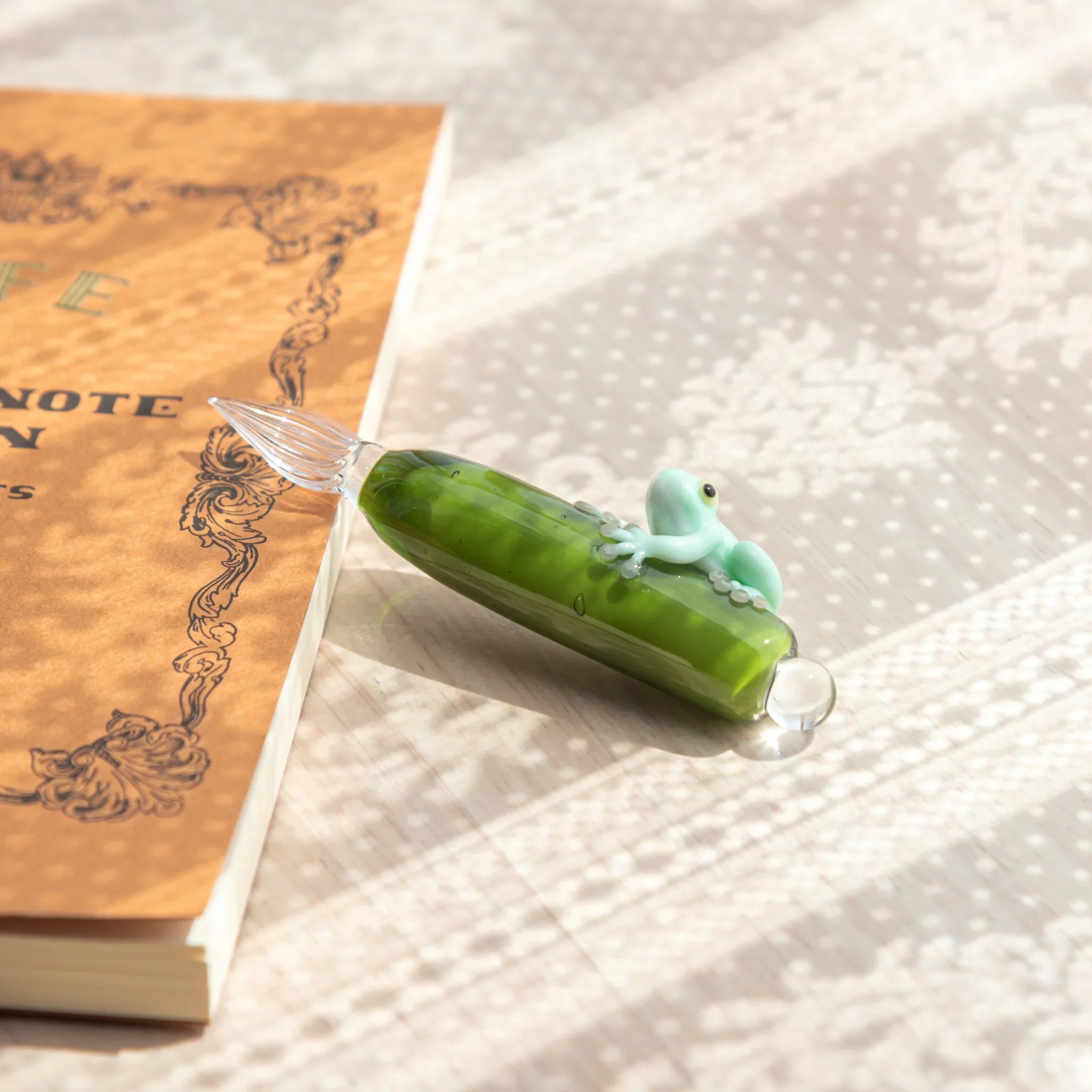 hand-made frog glass dip pen with pale green design carefully wrapped around colored glass ink barrel