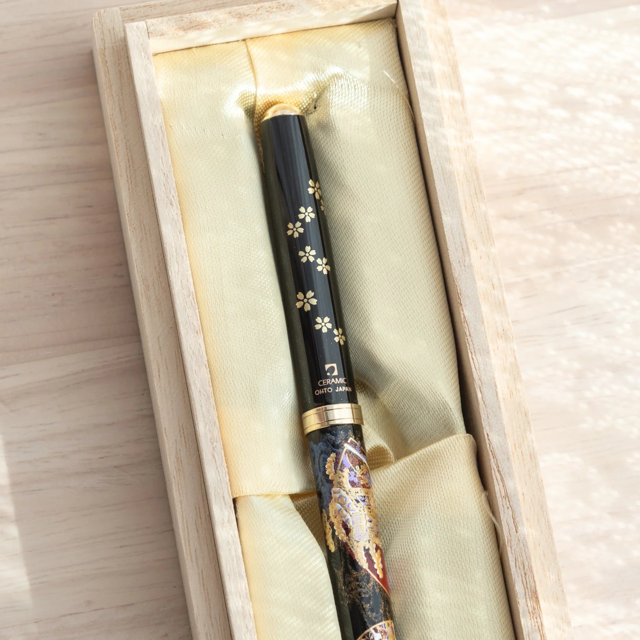 Yamanaka Japanese ballpoint pen in paulownia gift box, cap end close-up showing sakura blossoms, gold finial, OHTO JAPAN