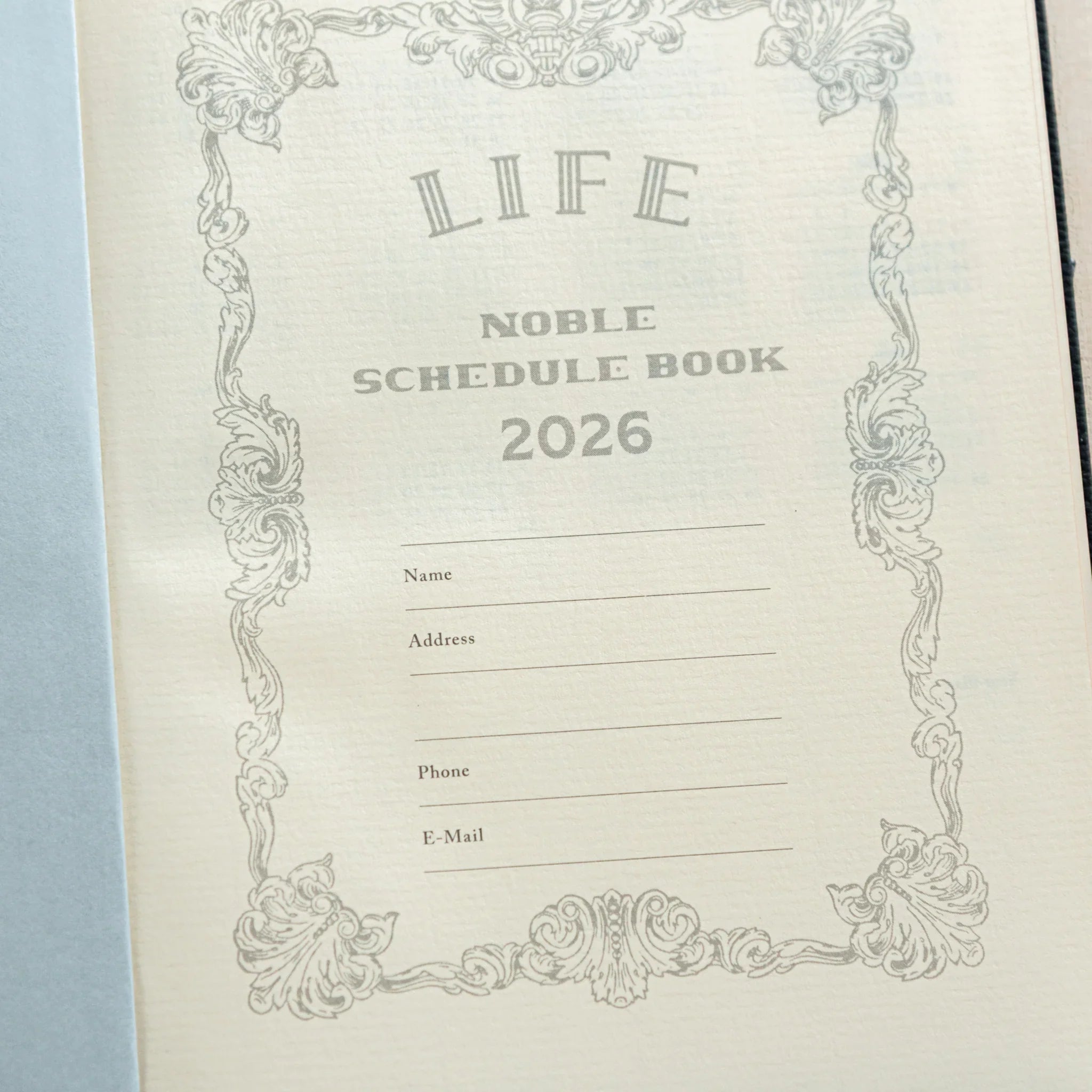 Life Noble 2026 hardcover planner featuring dark tone, open showing pages showing gold lettering              
