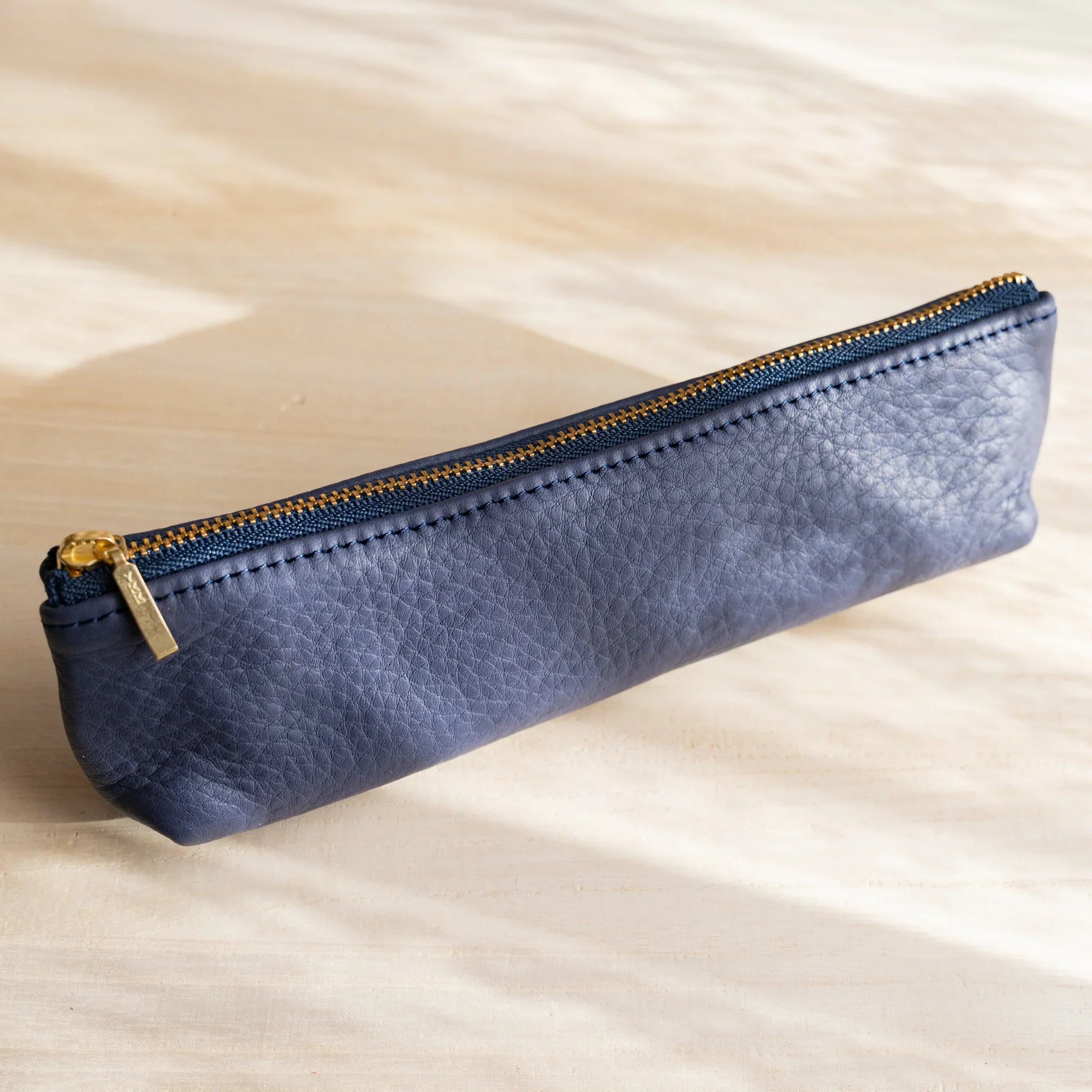 Life steerhide leather pen case in navy with gold zipper and cylindrical design and features and features
