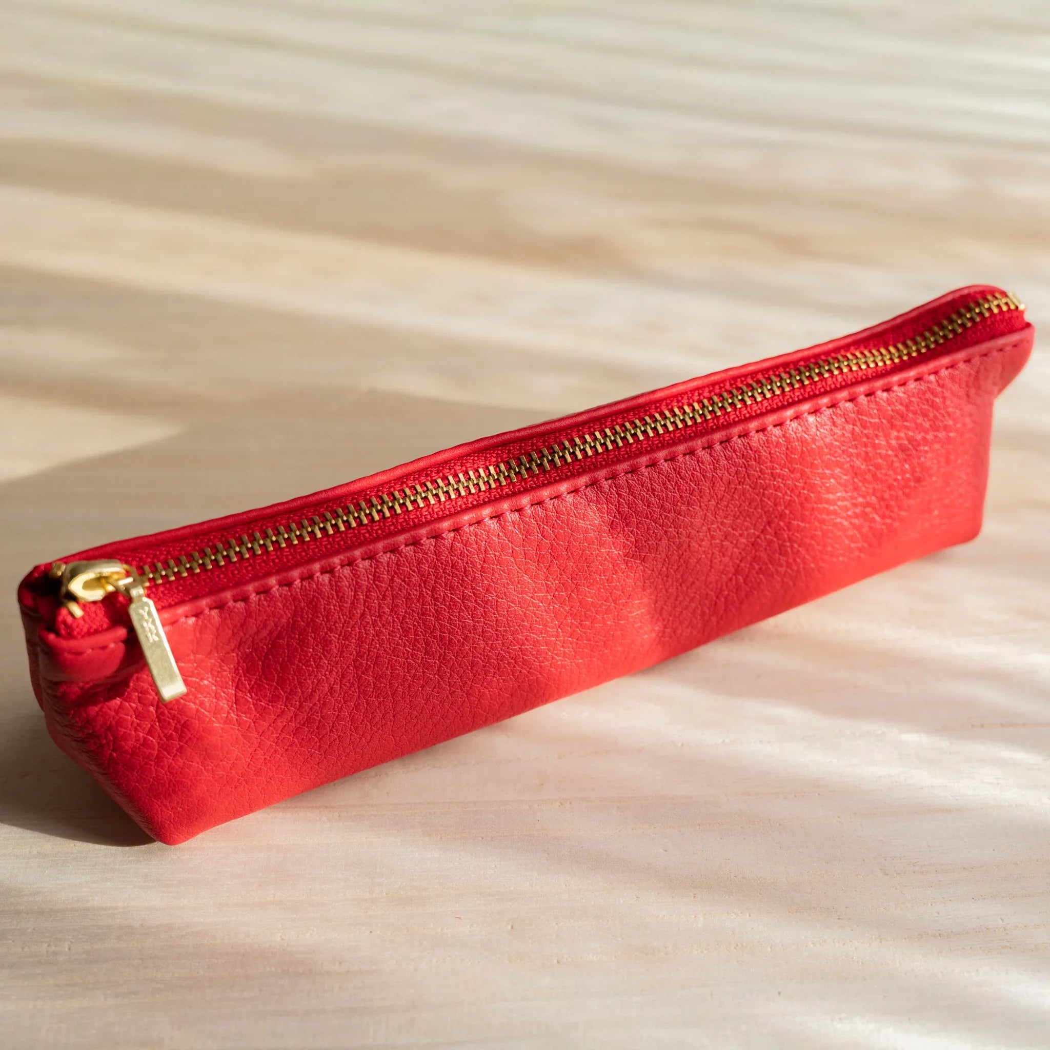 Life steerhide leather pen case in red with gold zipper and cylindrical form and features and features