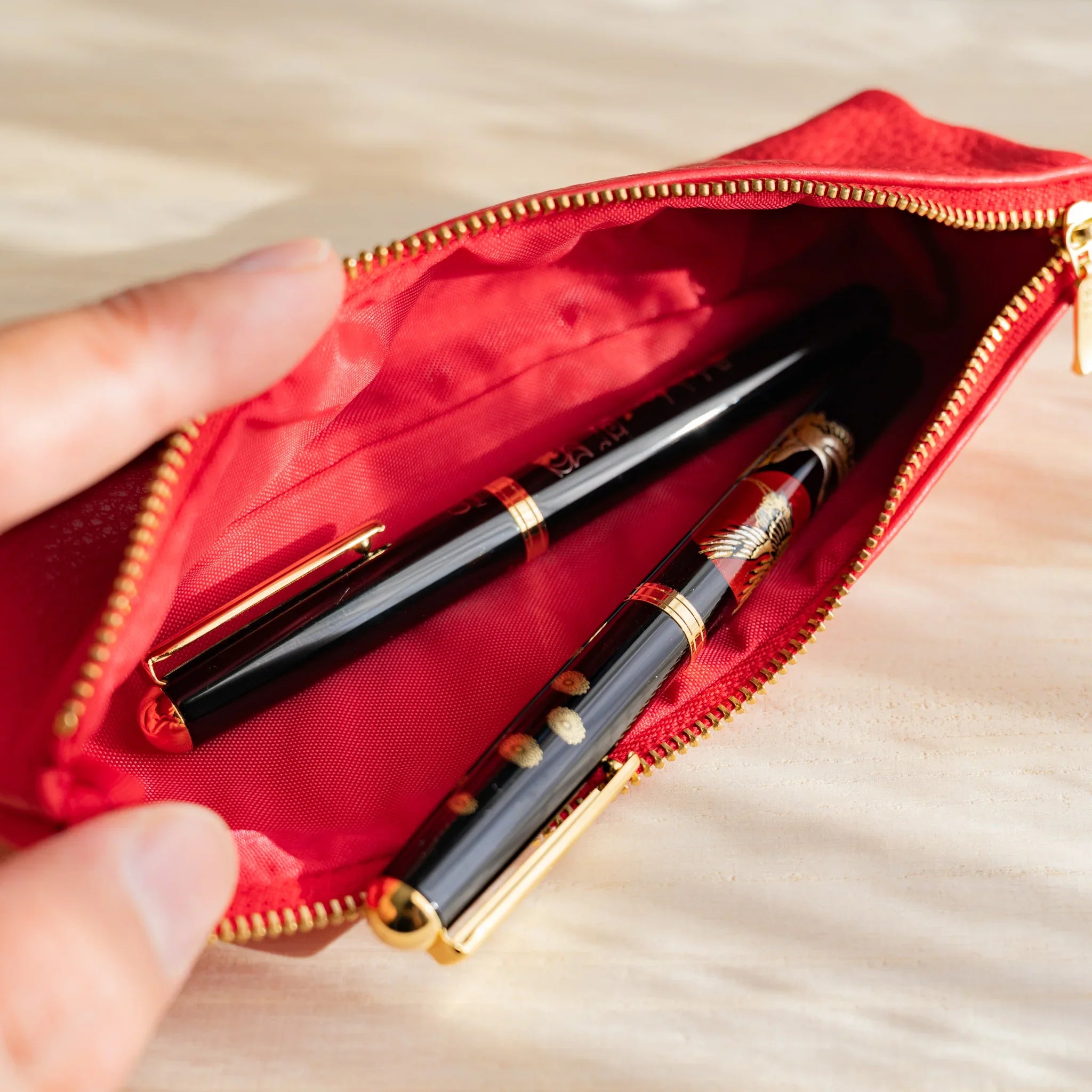Zipper detail on red case showing gold metal hardware and features and features and features and features