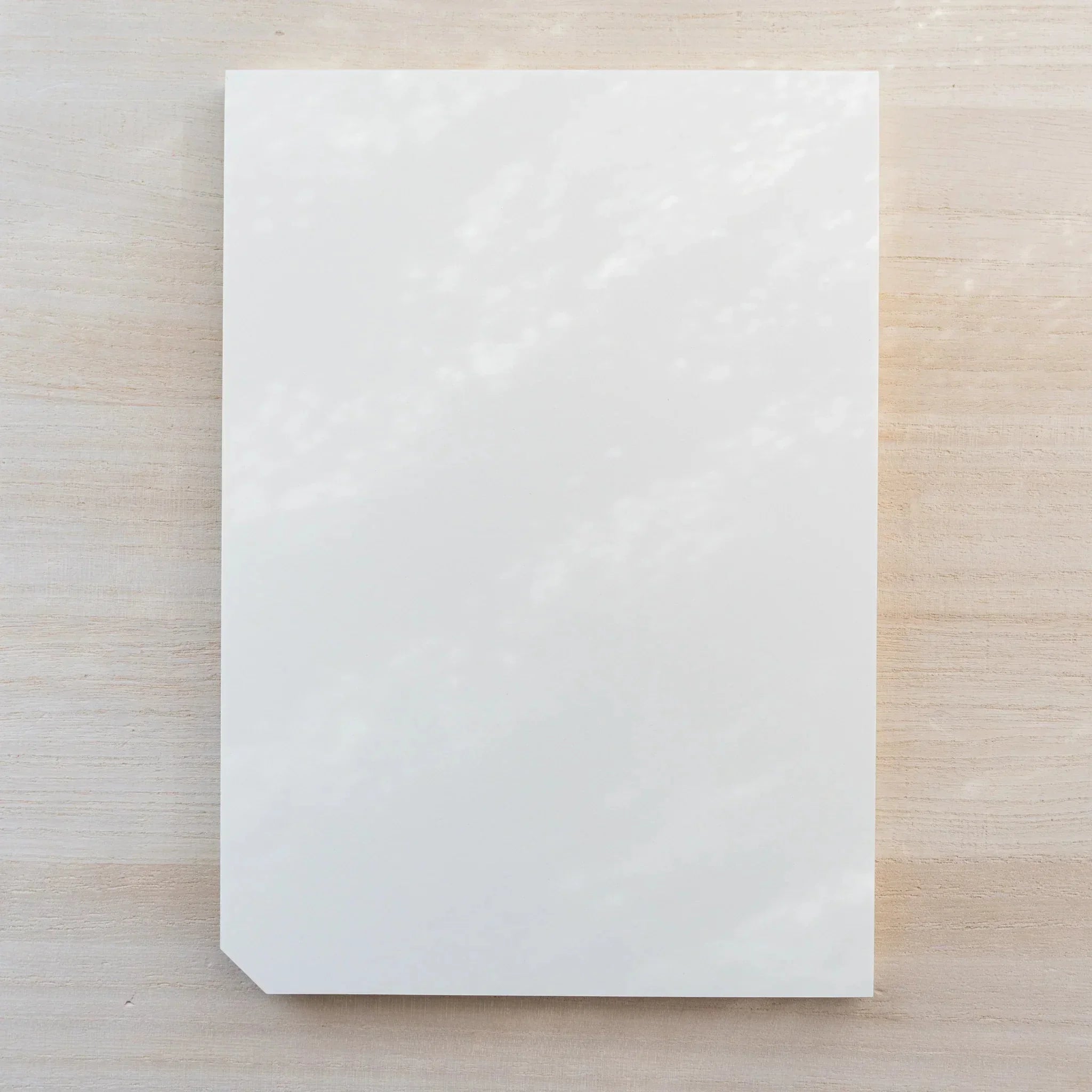 Midori MD Paper Pad A5, plain blank white top sheet with one cut corner, no belly band, on light wood