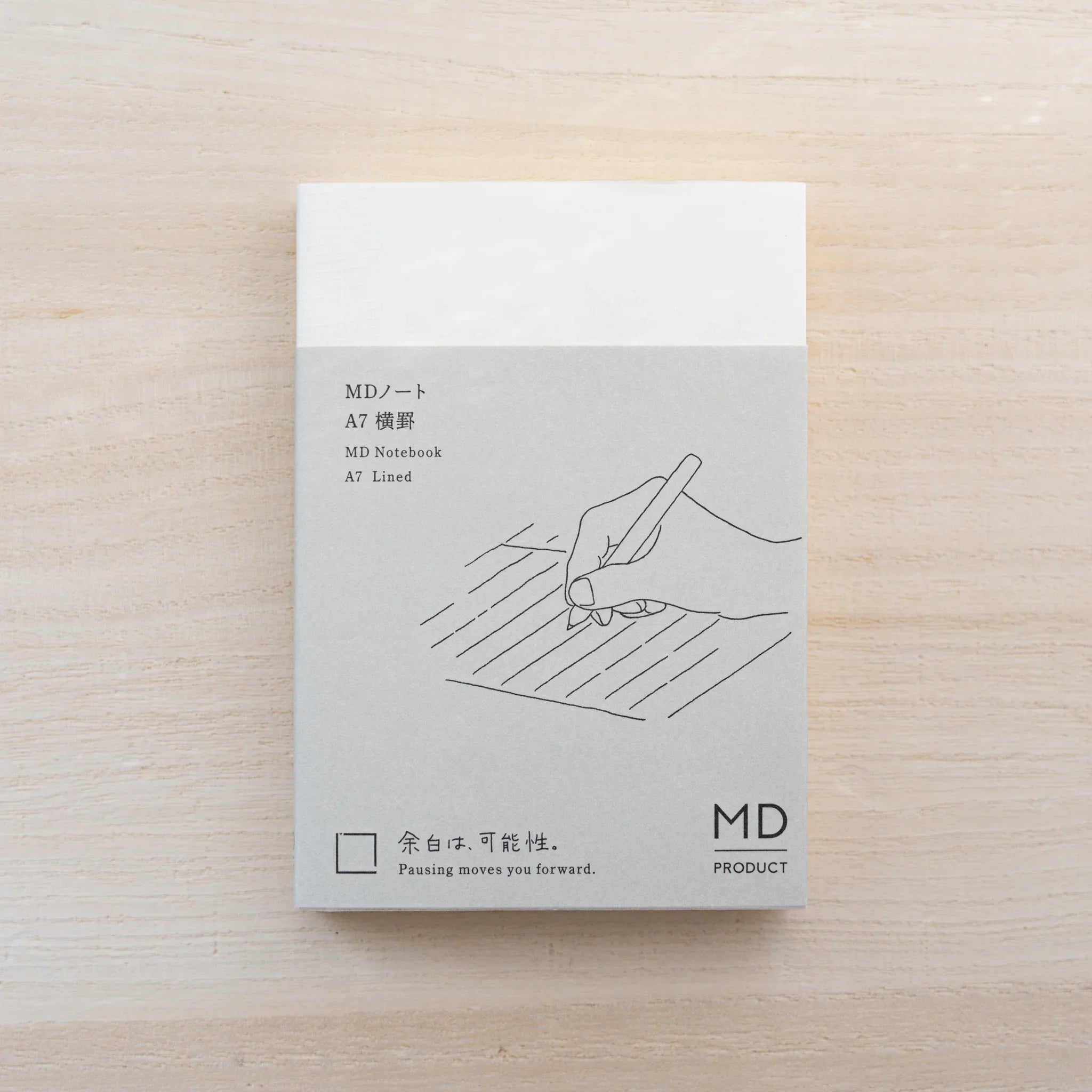 MD Notebook A7 in cream cover with paper belly band and hand-with-pen line drawing