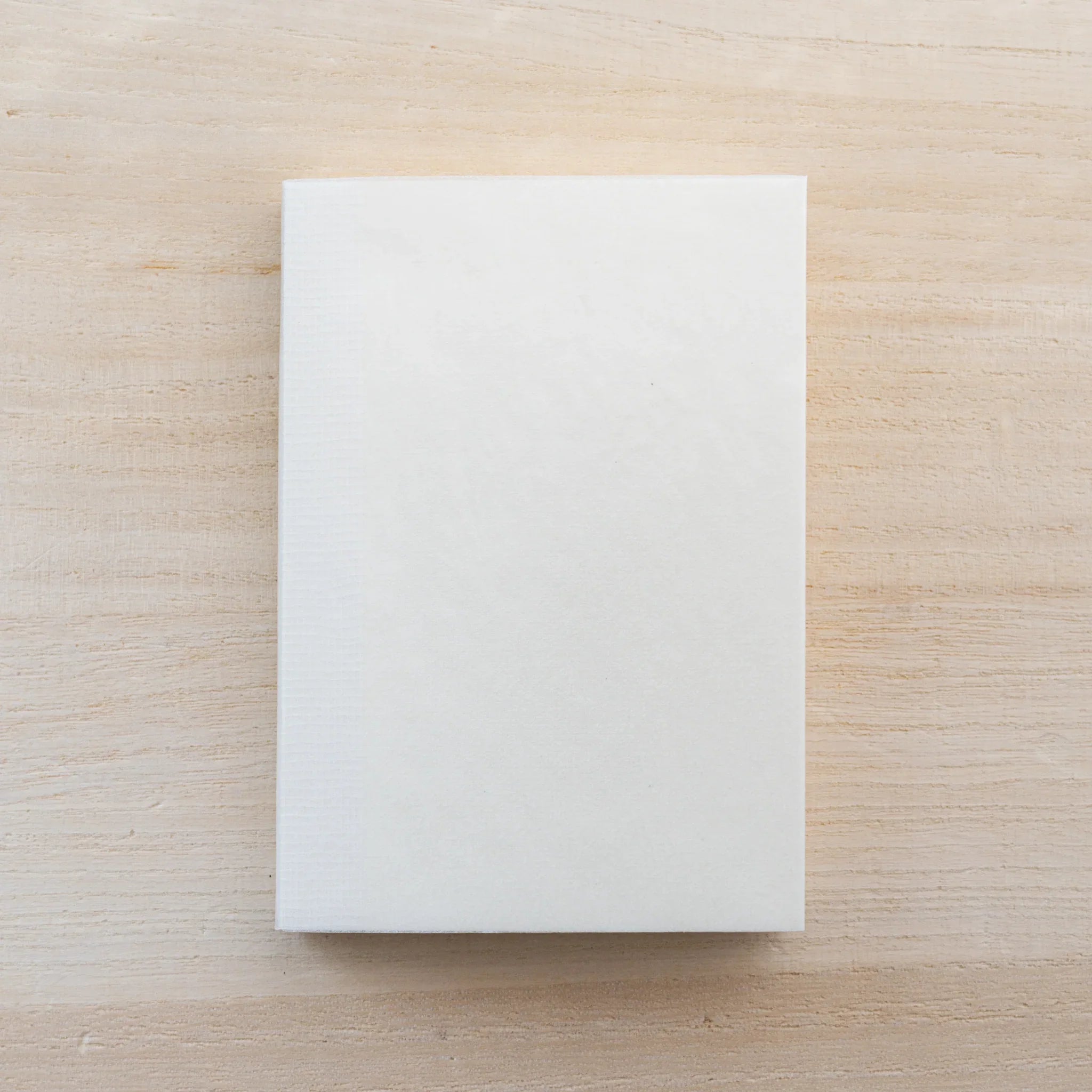 Cream MD Notebook A7, closed front cover on a wood surface
