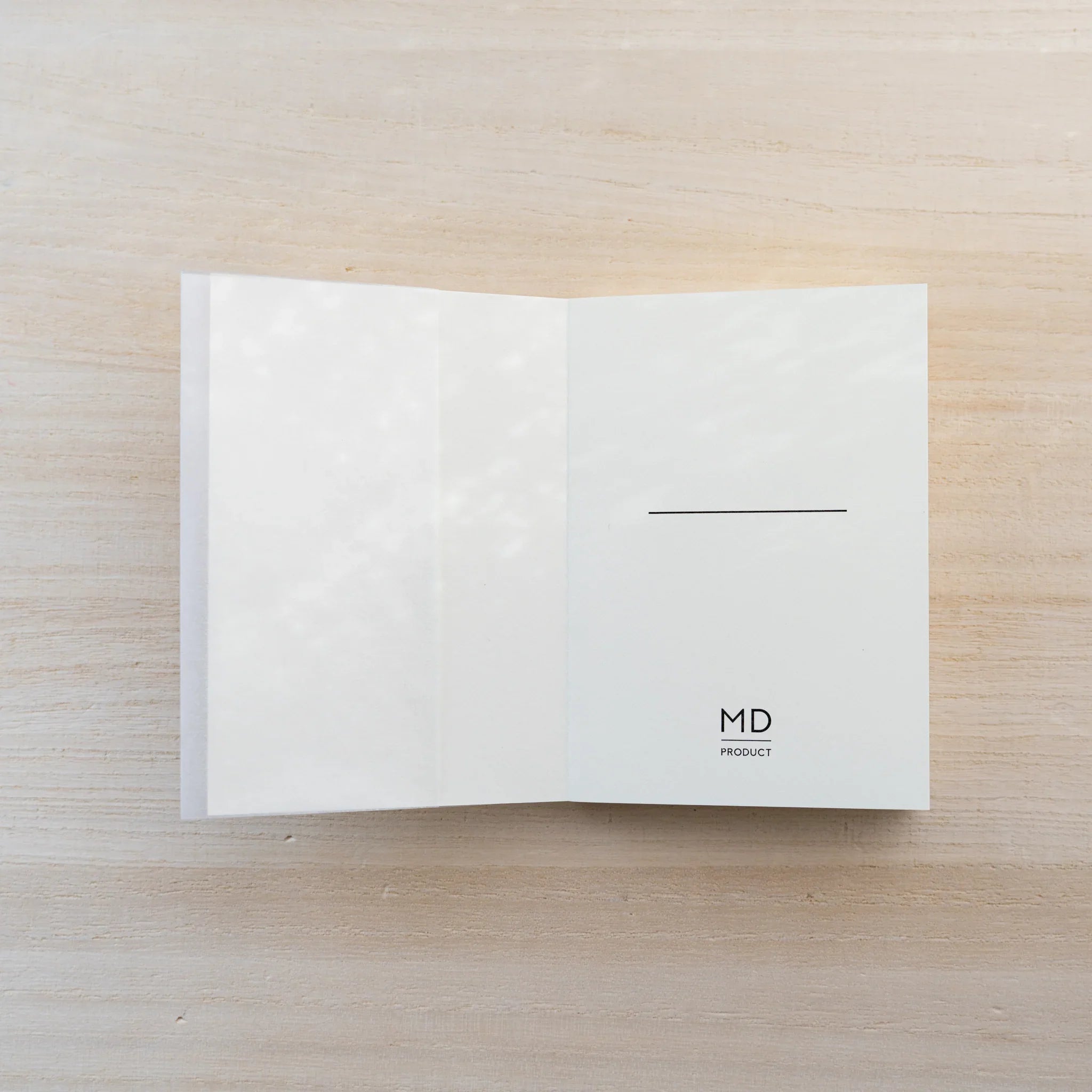MD Notebook A7 opened flat, blank cream spread with small MD logo