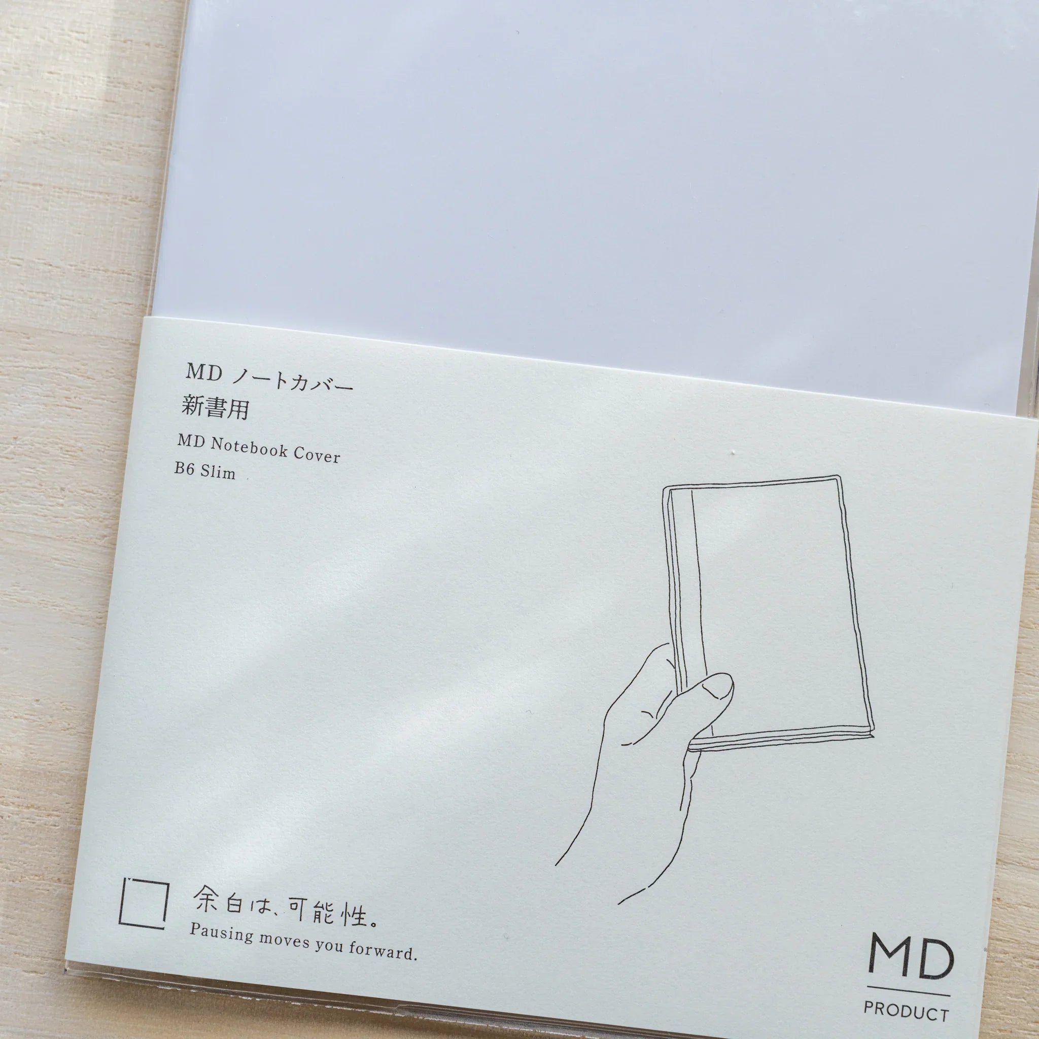 Insert card for Midori MD Notebook Cover B6 Slim with hand holding a notebook and MD PRODUCT logo