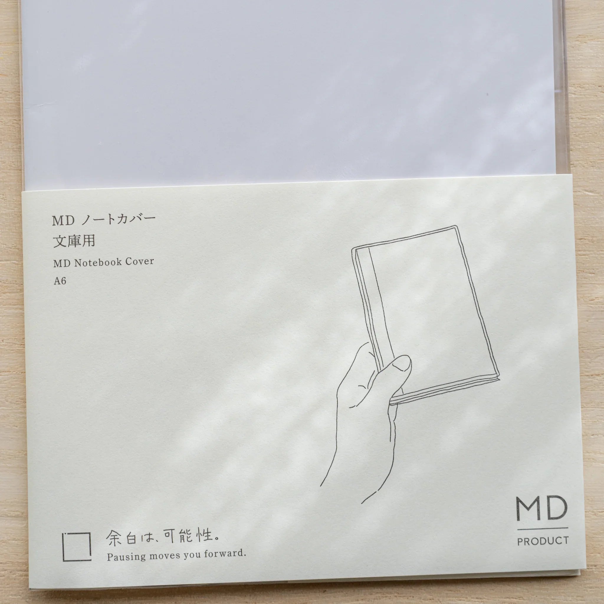 Insert card for Midori MD Notebook Cover A6 with line drawing of a hand holding a notebook