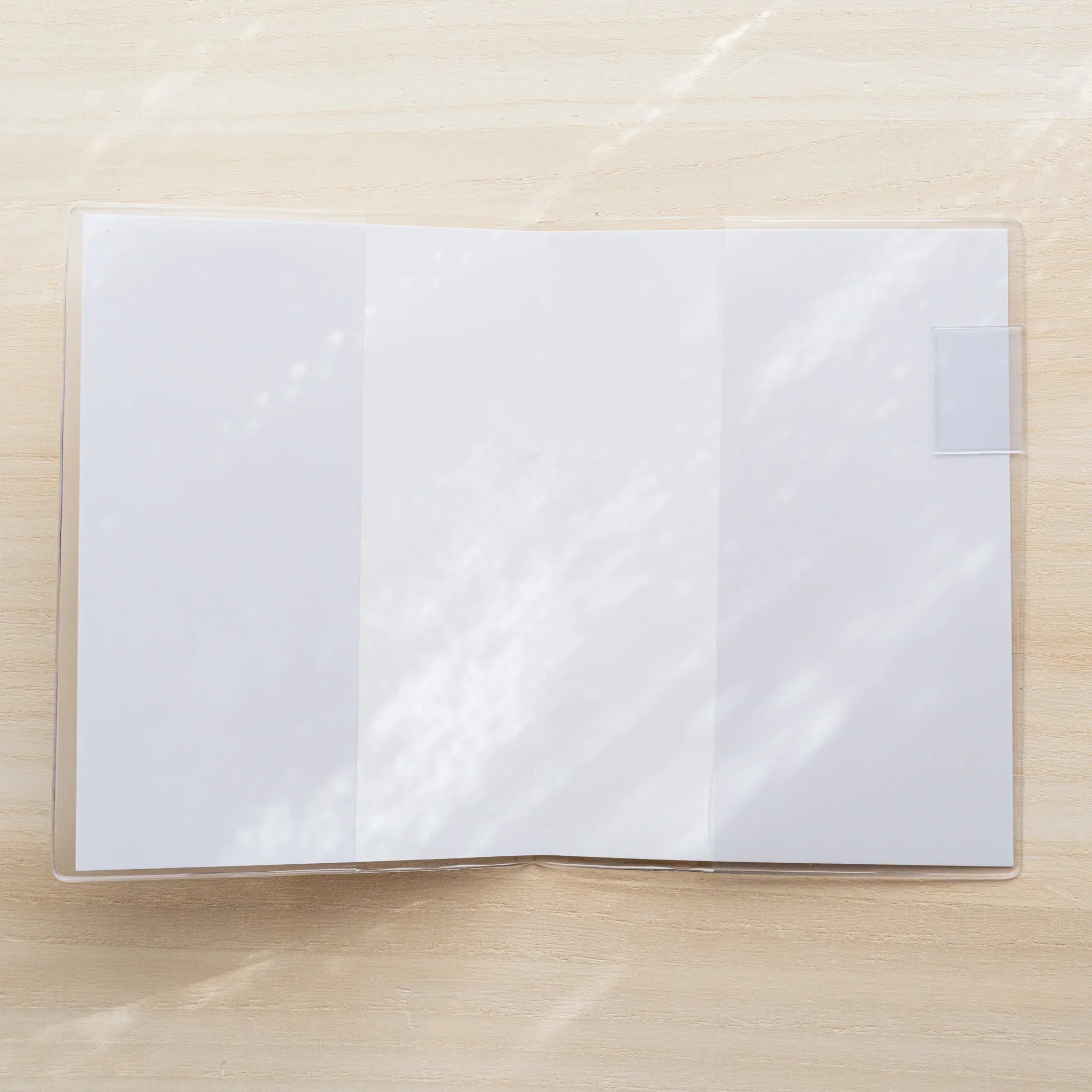 Midori MD Notebook Cover opened flat in clear PVC showing a blank white spread and center fold