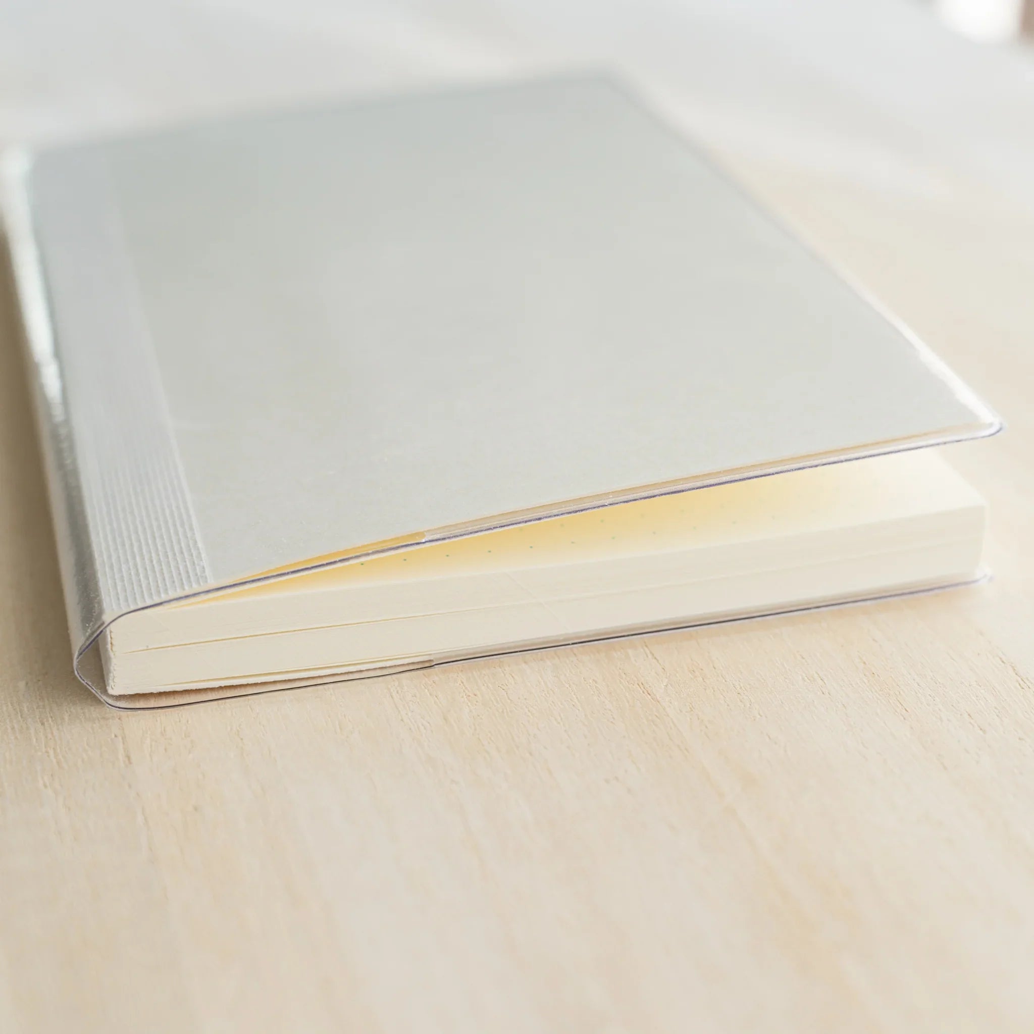 White MD notebook in clear PVC cover, angled view showing ivory dot grid page edges