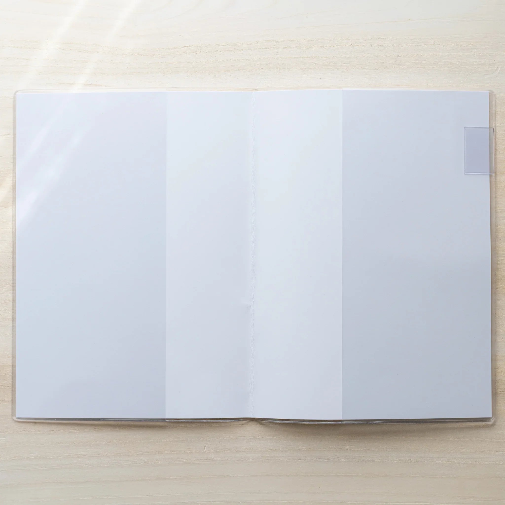 Midori MD Notebook Cover opened flat in clear PVC showing a blank white spread and center fold