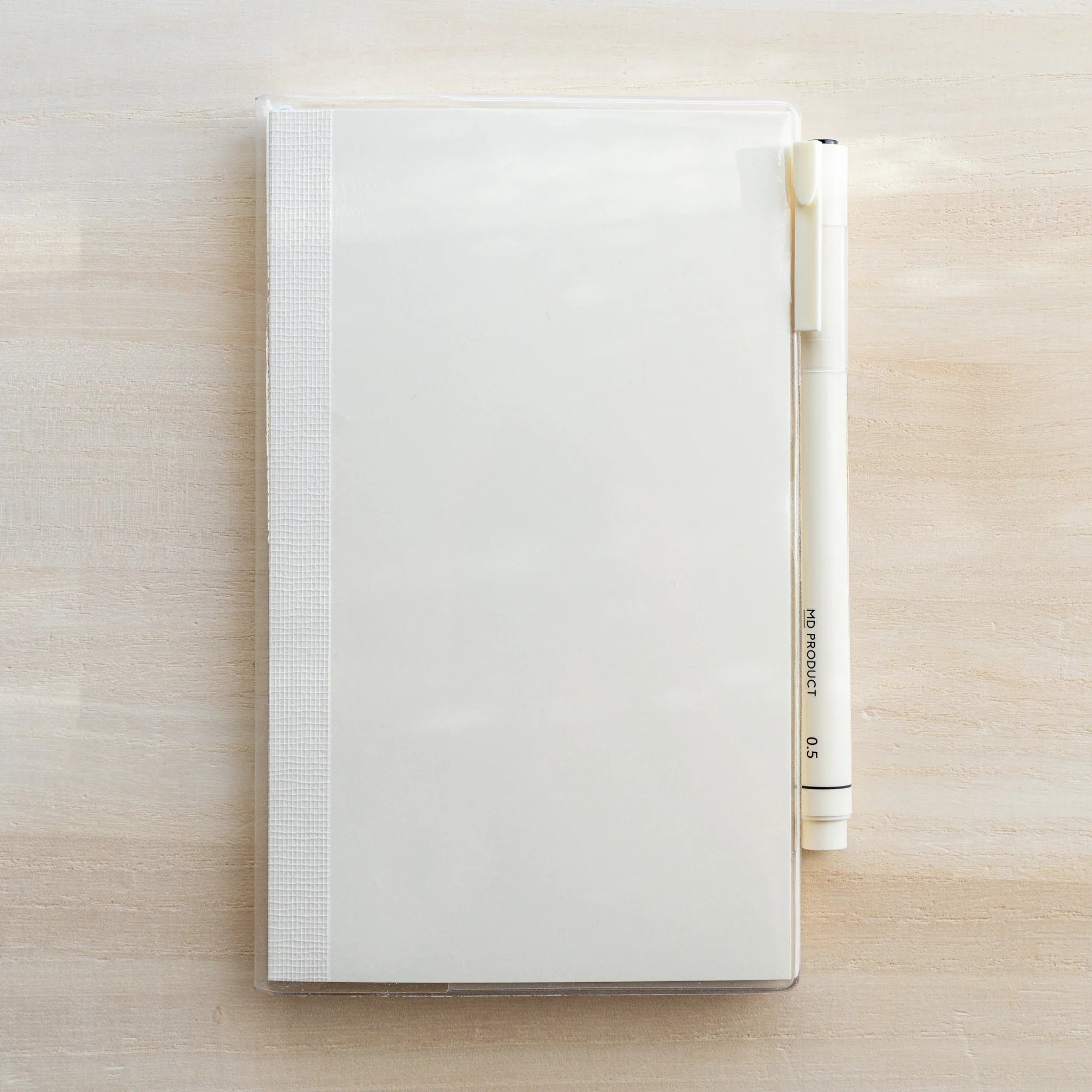 White MD notebook in clear PVC cover with a white MD PRODUCT pen in the side pen holder