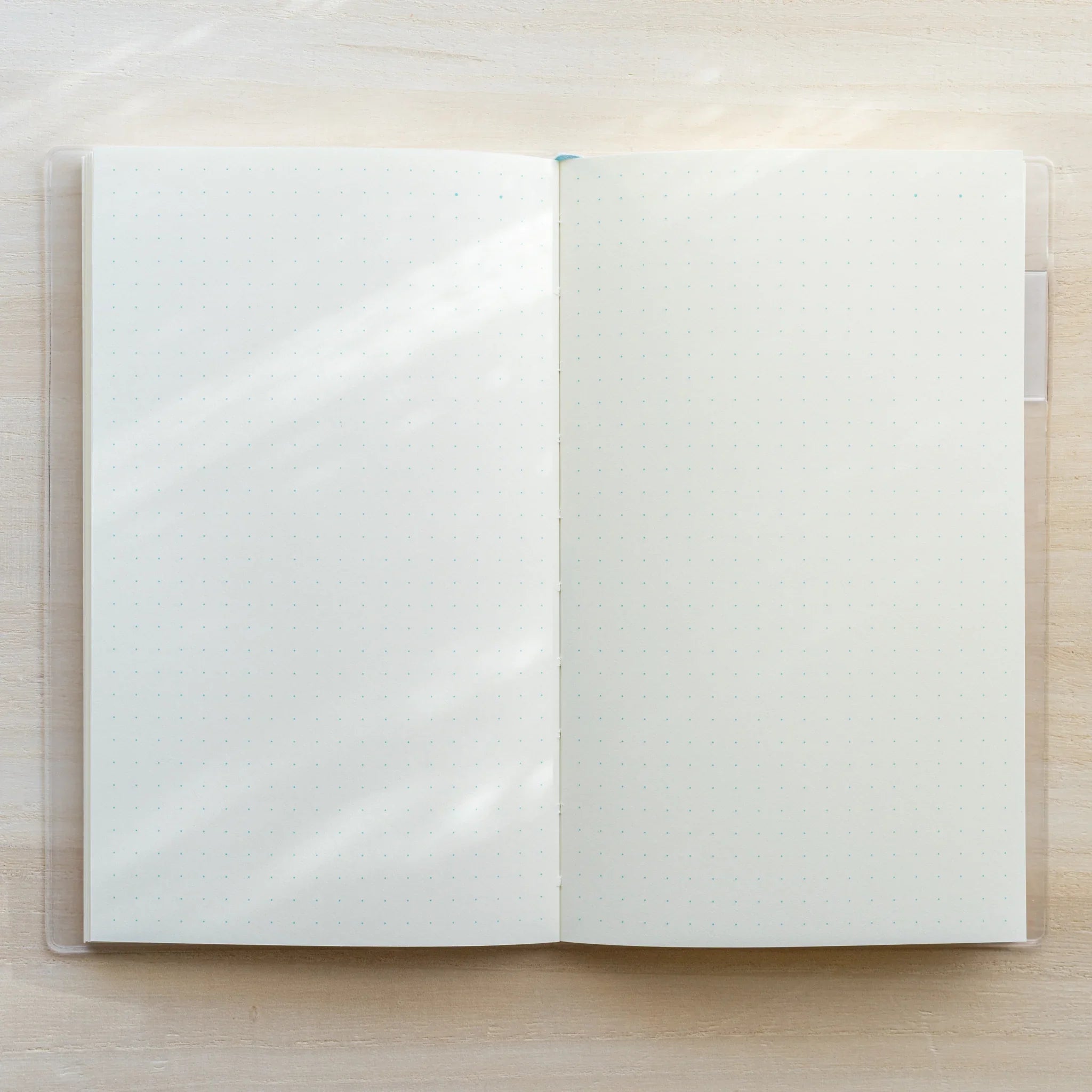 Open MD notebook in clear PVC cover, blank white two-page spread with visible center spine