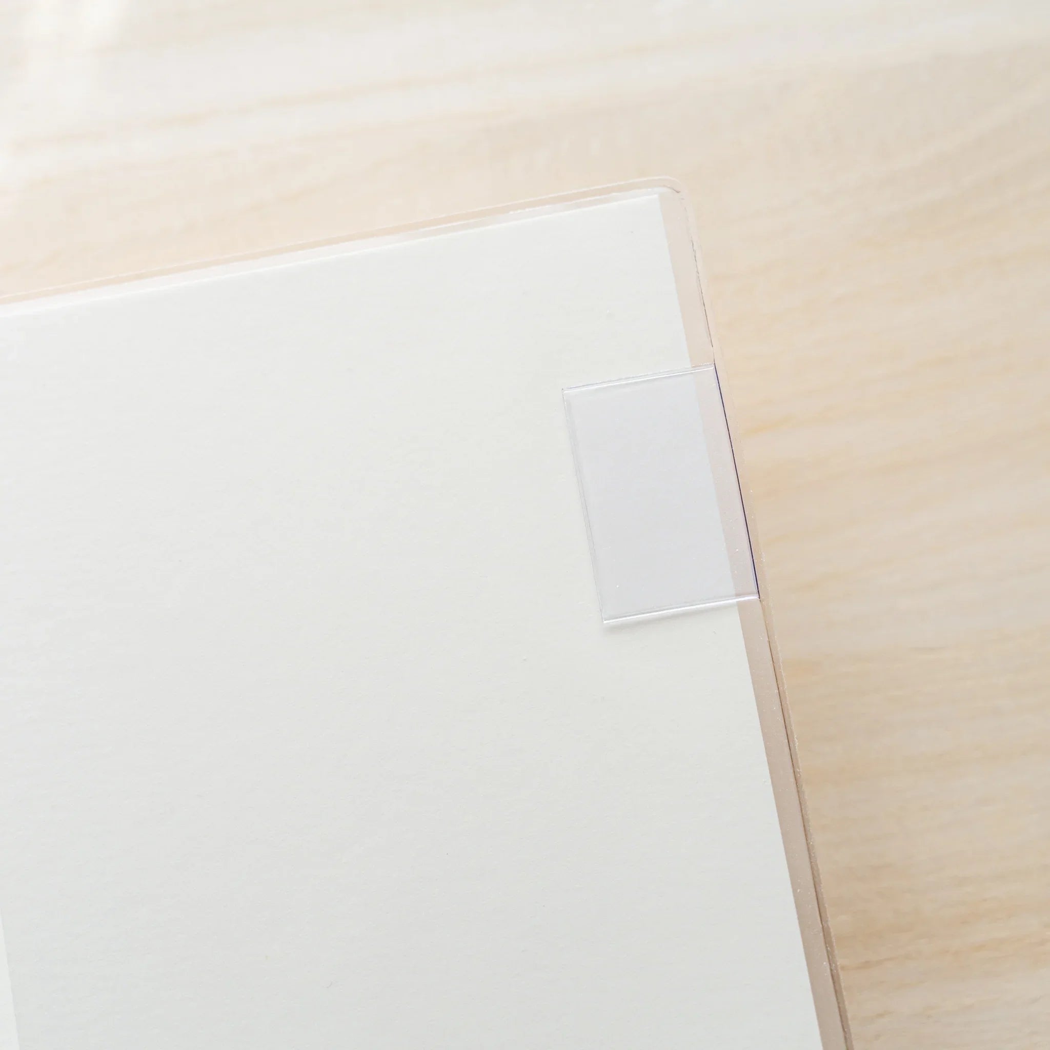 Close-up of clear PVC Midori MD Notebook Cover corner with a small white plastic bookmark tab