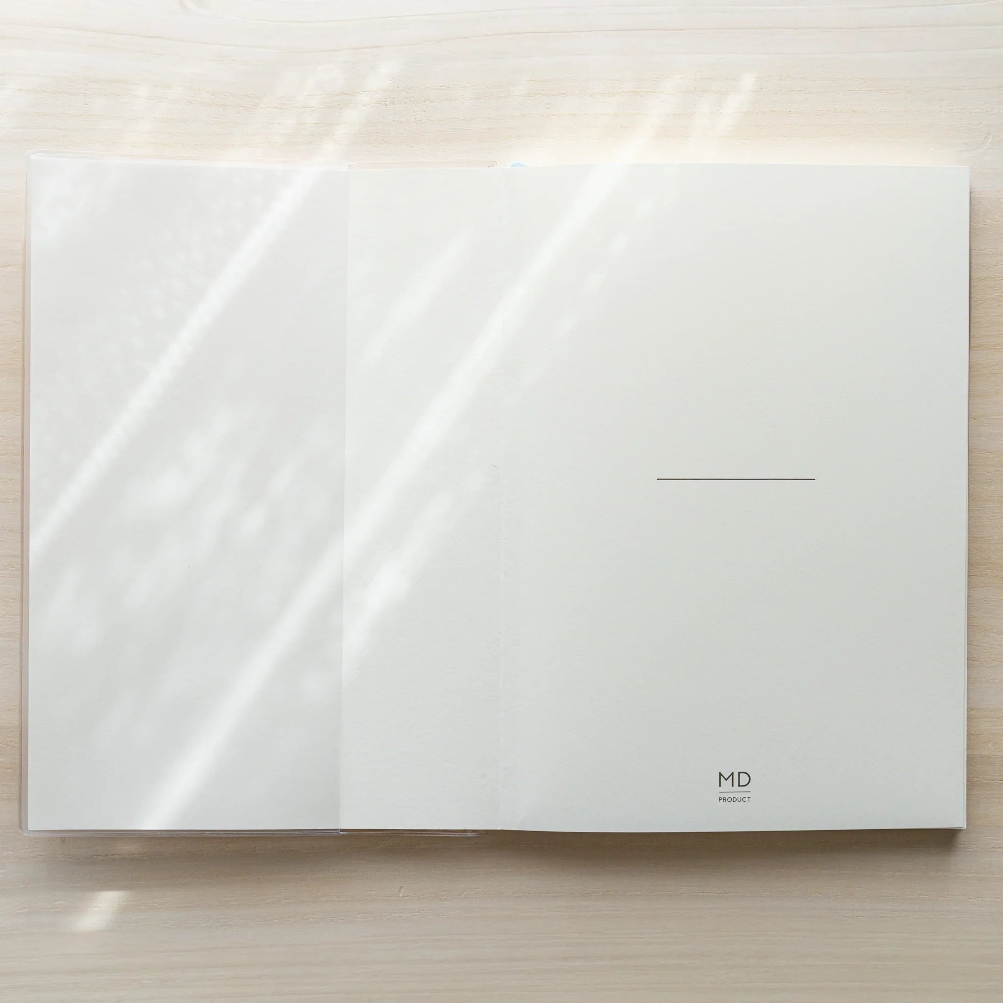 Midori MD Notebook Cover opened flat in clear PVC showing a blank white spread with MD PRODUCT logo