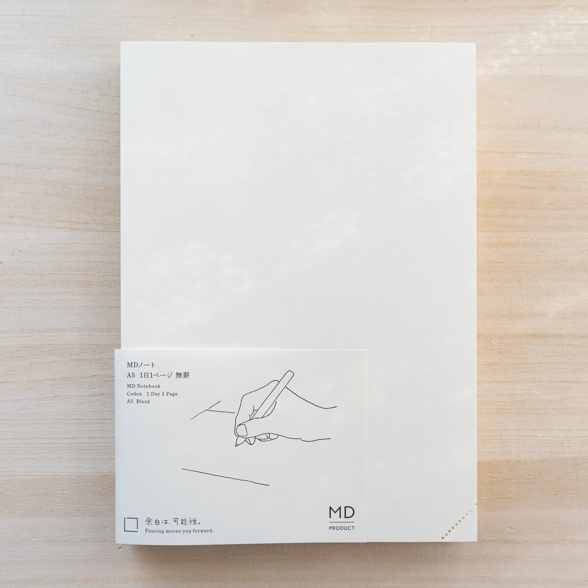 Midori MD Notebook white cover with paper belly band reading MD Notebook 1 Day 1 Page A5 Blank, hand-writing line drawing