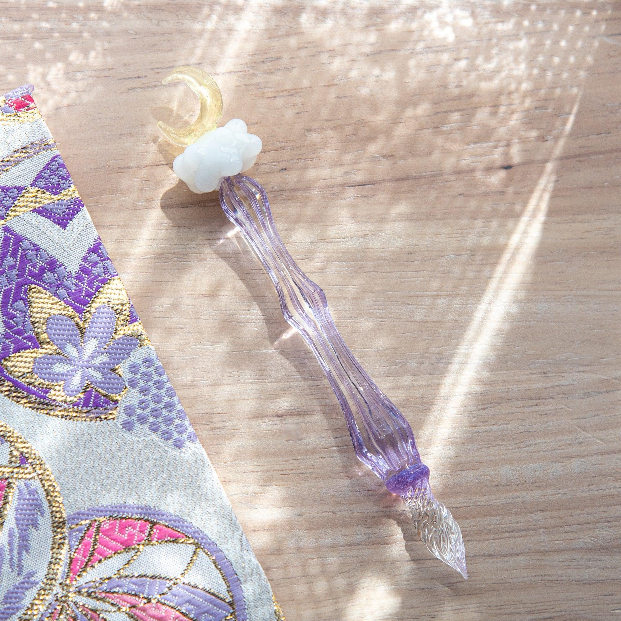 Japanese glass dip pen with white ceramic cloud-shaped topper and purple ribbed textured glass barrel, lifestyle shot
