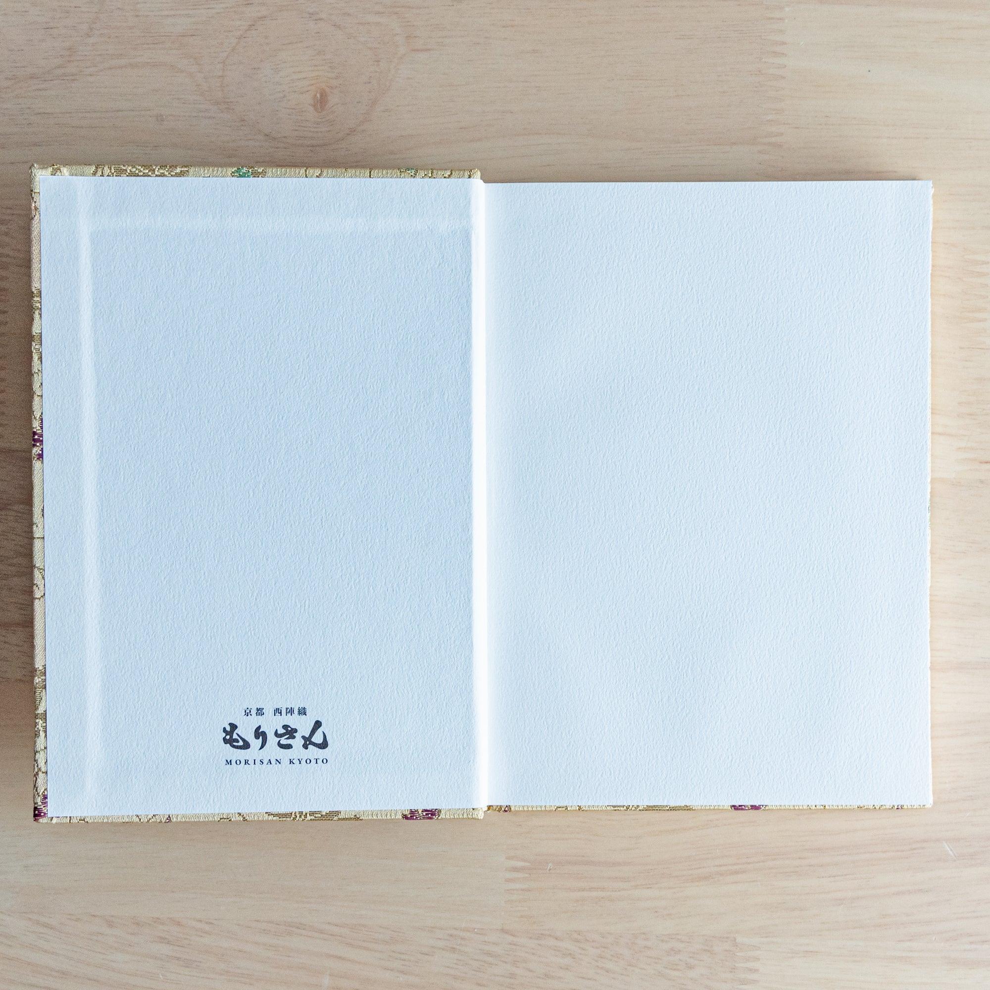 Opened Nishijin textile Japanese notebook with white endpaper and Morisan Kyoto branding on left and blank white right page
